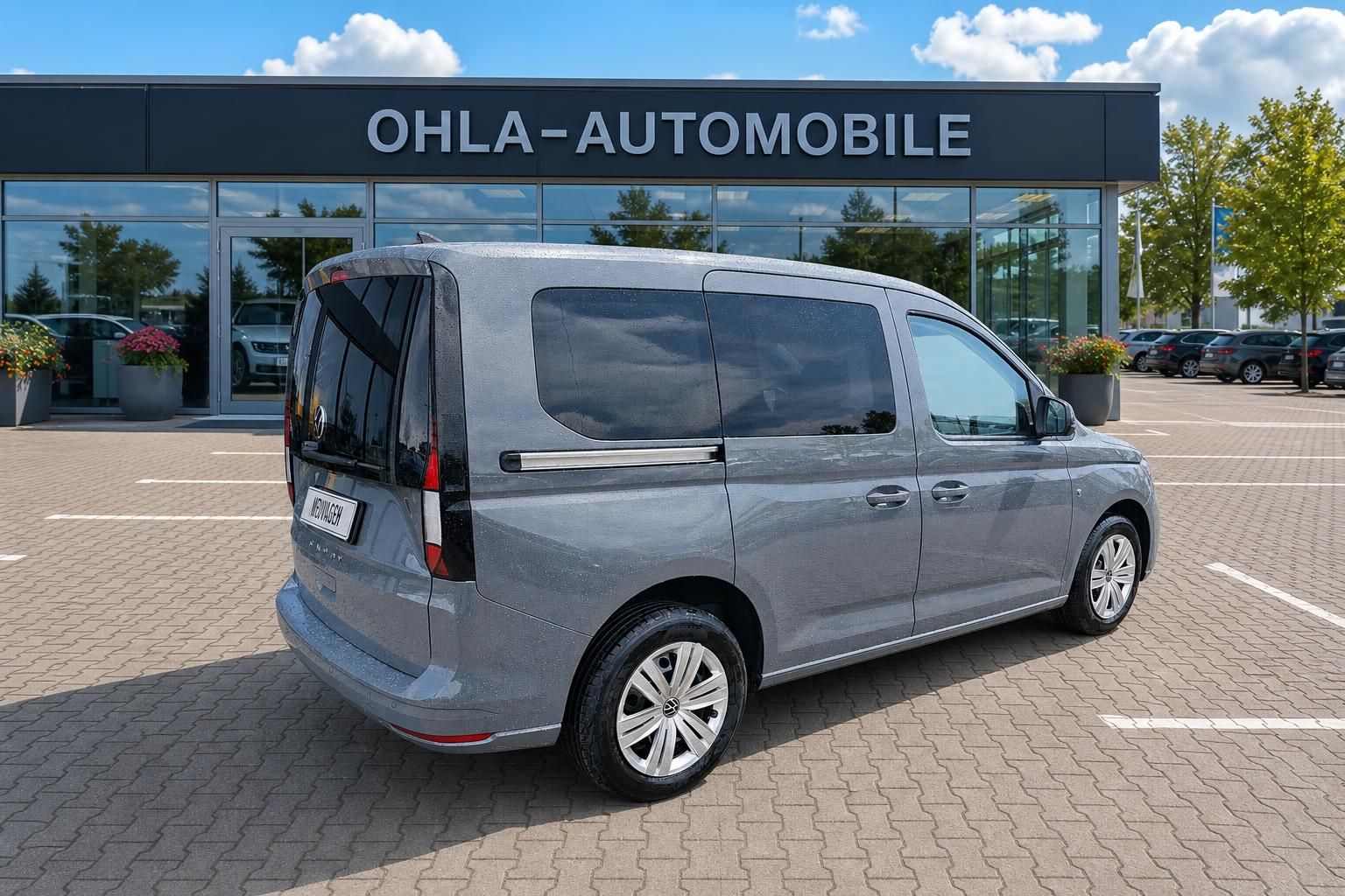 VW Caddy grau Seitenansicht hinten vor Autohaus OHLA-Automobile