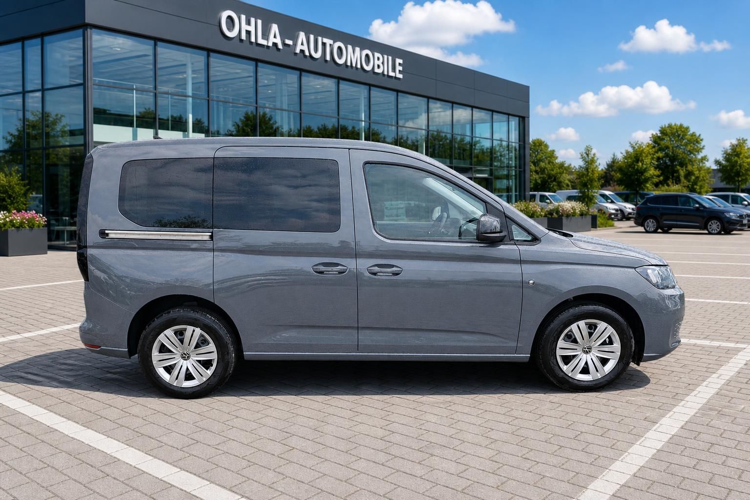 VW Caddy grau Seitenansicht vor Autohaus OHLA-Automobile
