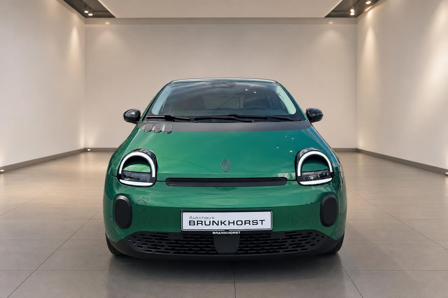 Grüner Renault Twingo Elektroauto Frontansicht in Ausstellungsraum mit charakteristischen runden Scheinwerfern