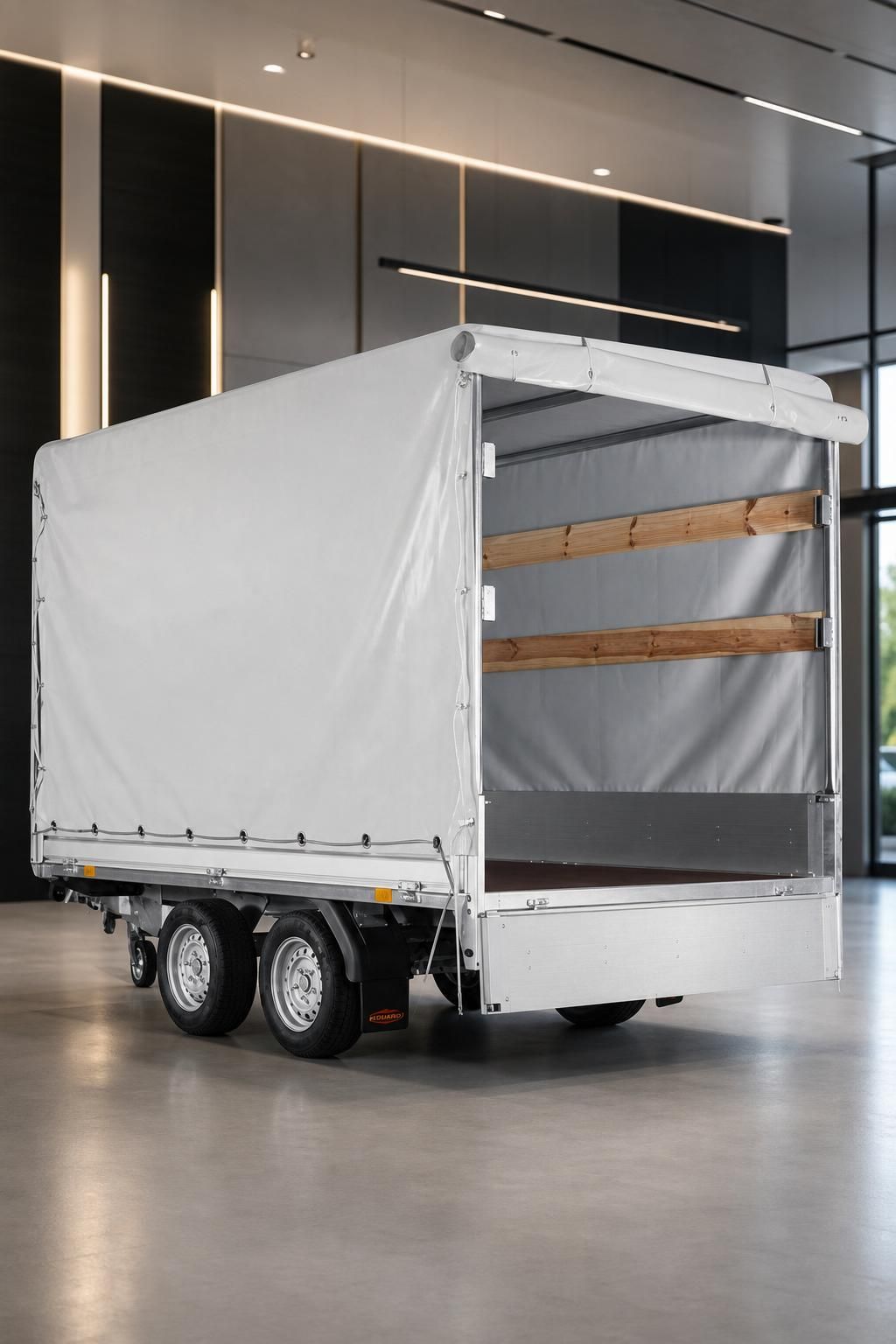 PKW-Anhänger mit weißer Plane und Holzaufbau im modernen Showroom