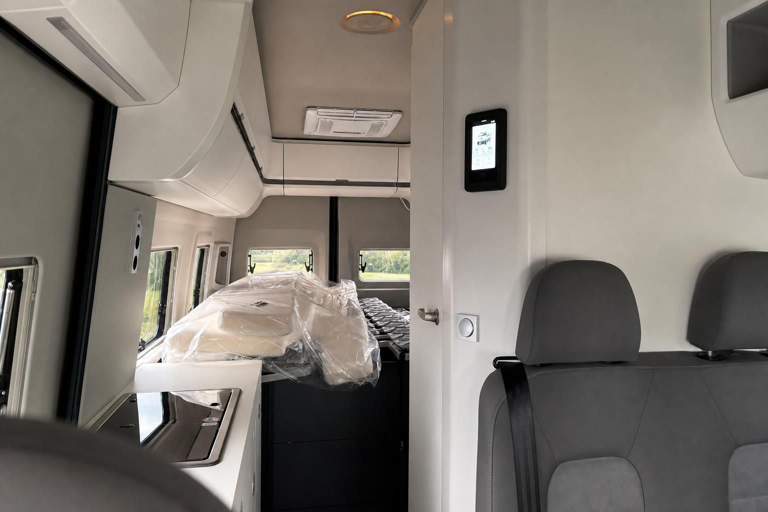 Wohnmobil Innenraum mit Bett, Küche und digitalem Bedienfeld