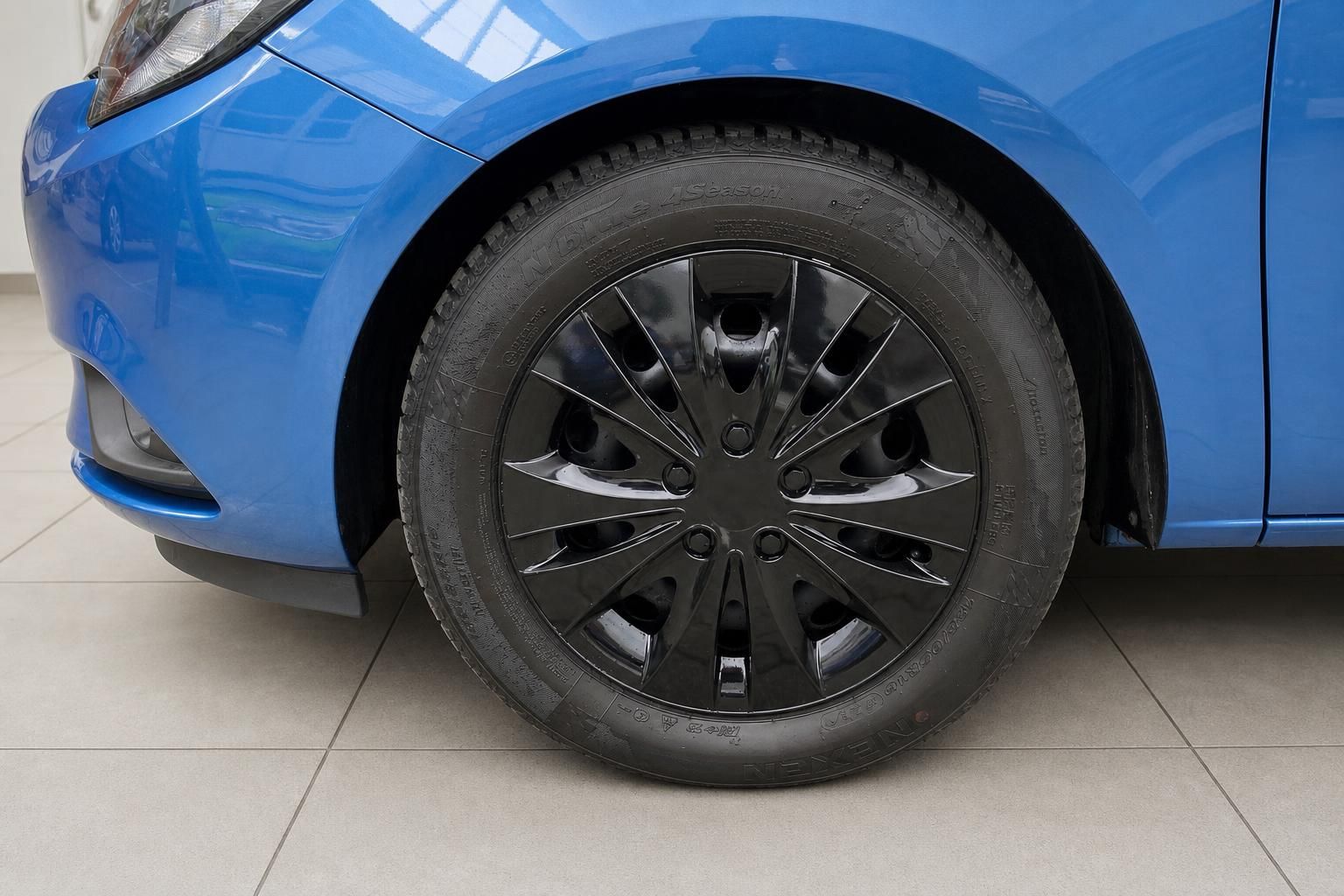 Blaues Auto Vorderrad mit schwarzer Felge und Reifen - Detailaufnahme Radkasten
