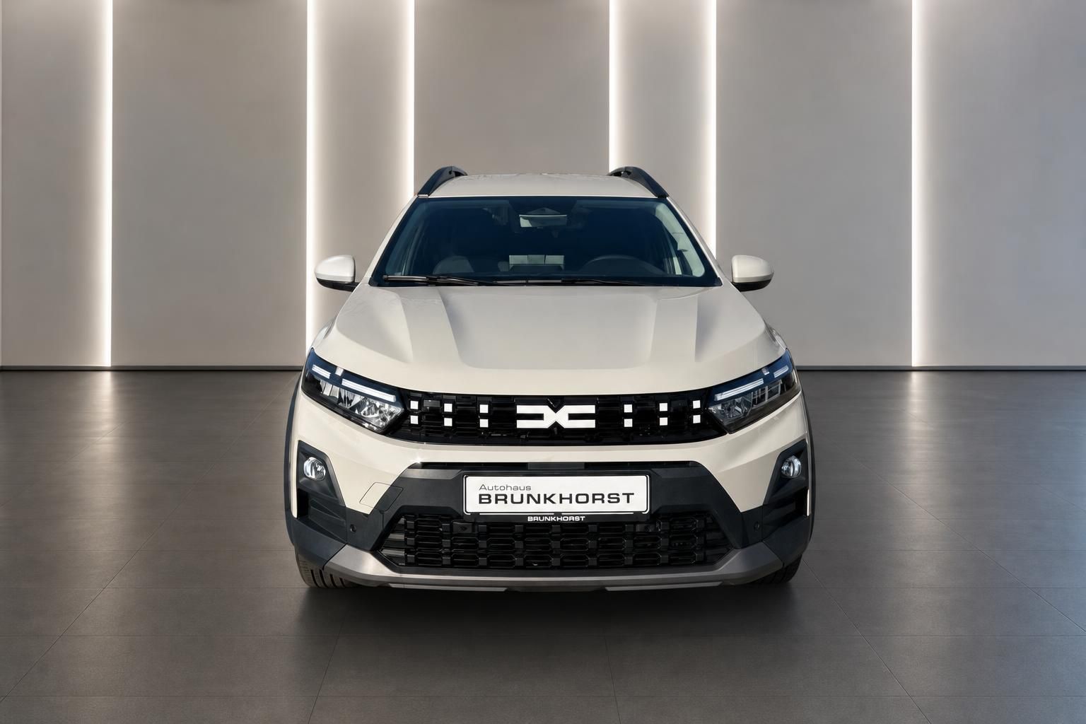 Dacia Jogger weiss Frontansicht zwischen weissen Säulen im modernen Autohaus Brunkhorst Showroom