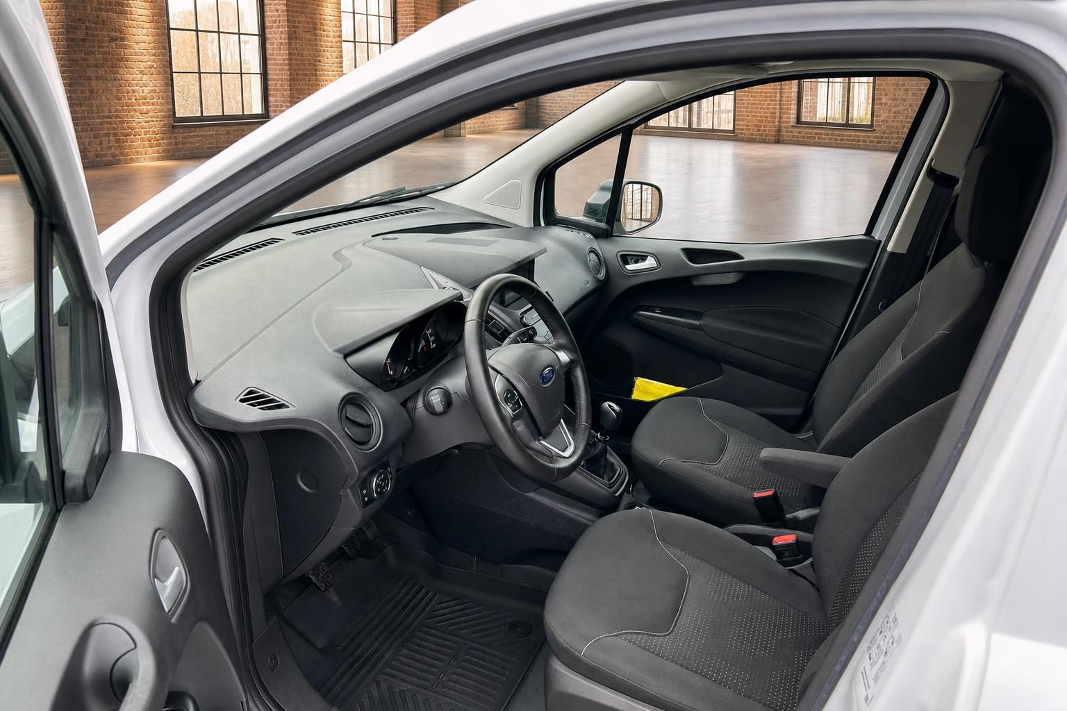 Ford Transit Courier Innenraum – Fahrersitz, Lenkrad mit Ford Logo und schwarzes Cockpit