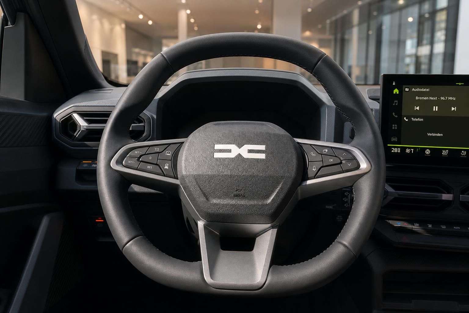 Detailaufnahme Lenkrad mit Markenlogo und Touchscreen-Display im modernen Fahrzeuginnenraum