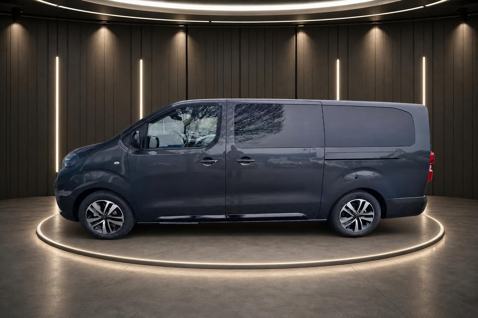 Dunkler Kleinbus Seitenansicht in modernem Showroom mit Beleuchtung auf rundem Podest
