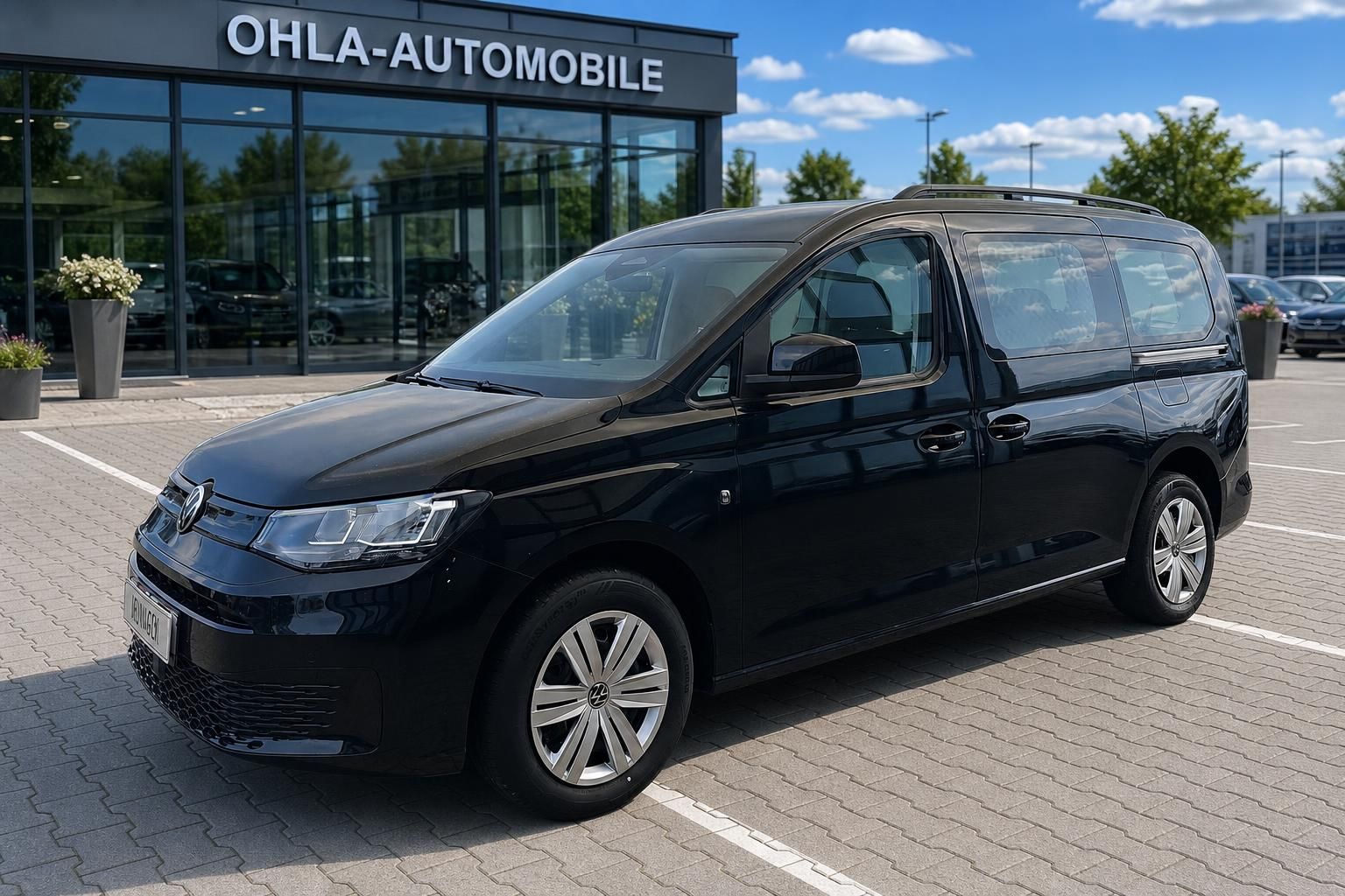 VW Caddy schwarz Frontansicht seitlich auf Hof des Autohauses