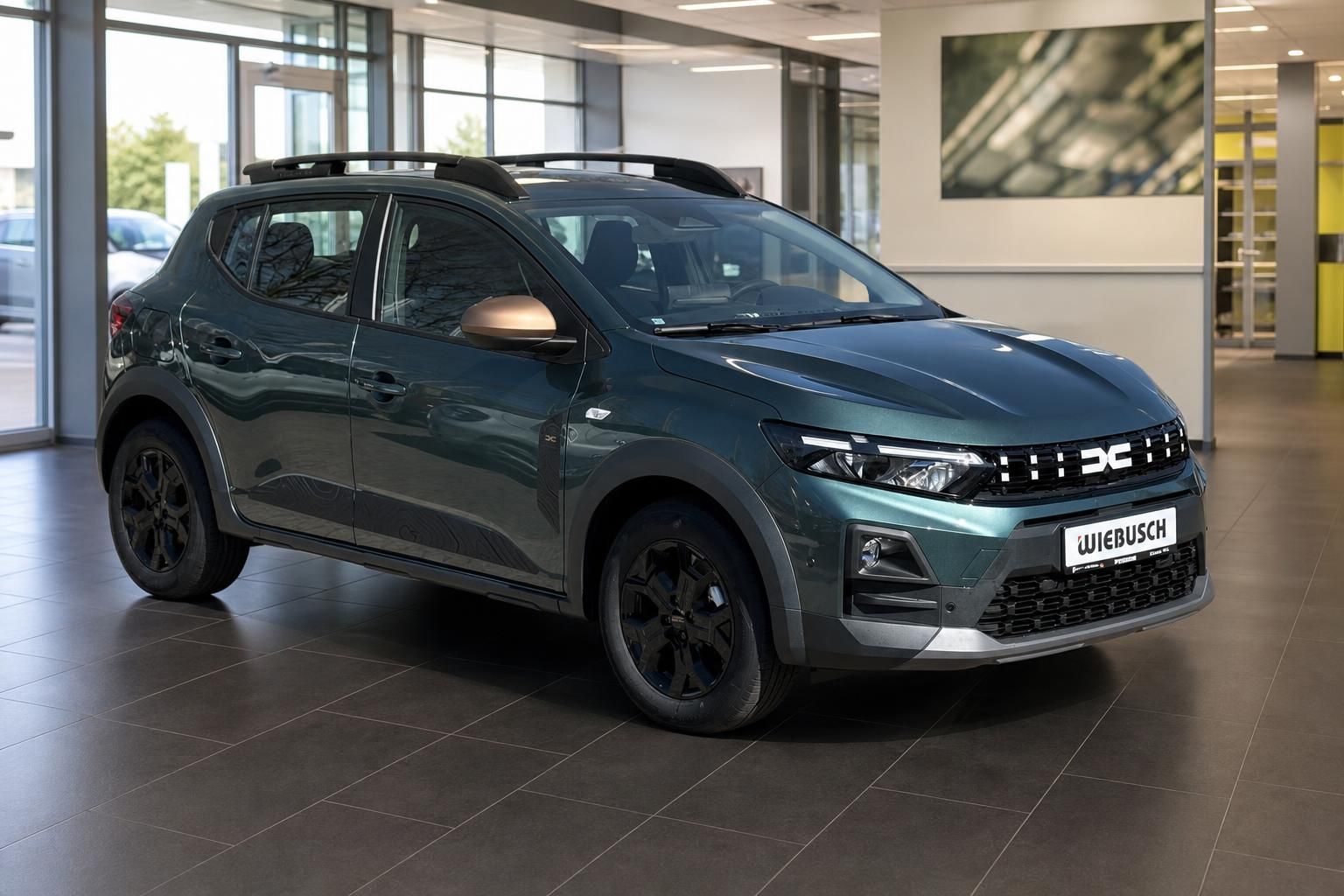 Dacia SUV Frontansicht schräg links in graugrün mit schwarzen Felgen und Wiebusch Kennzeichen