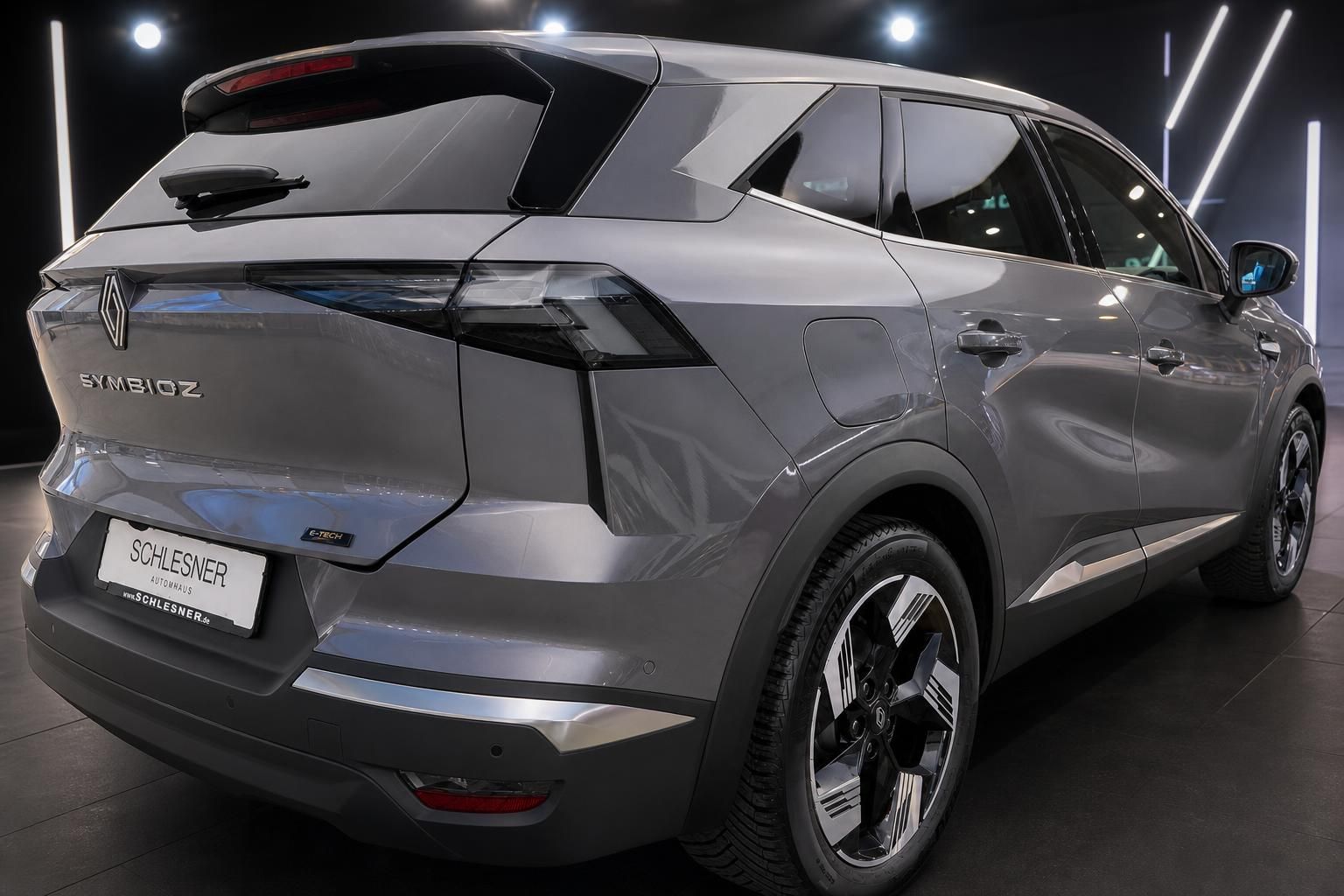 Renault Symbioz E-Tech in Grau, Heckansicht schräg im Autohaus