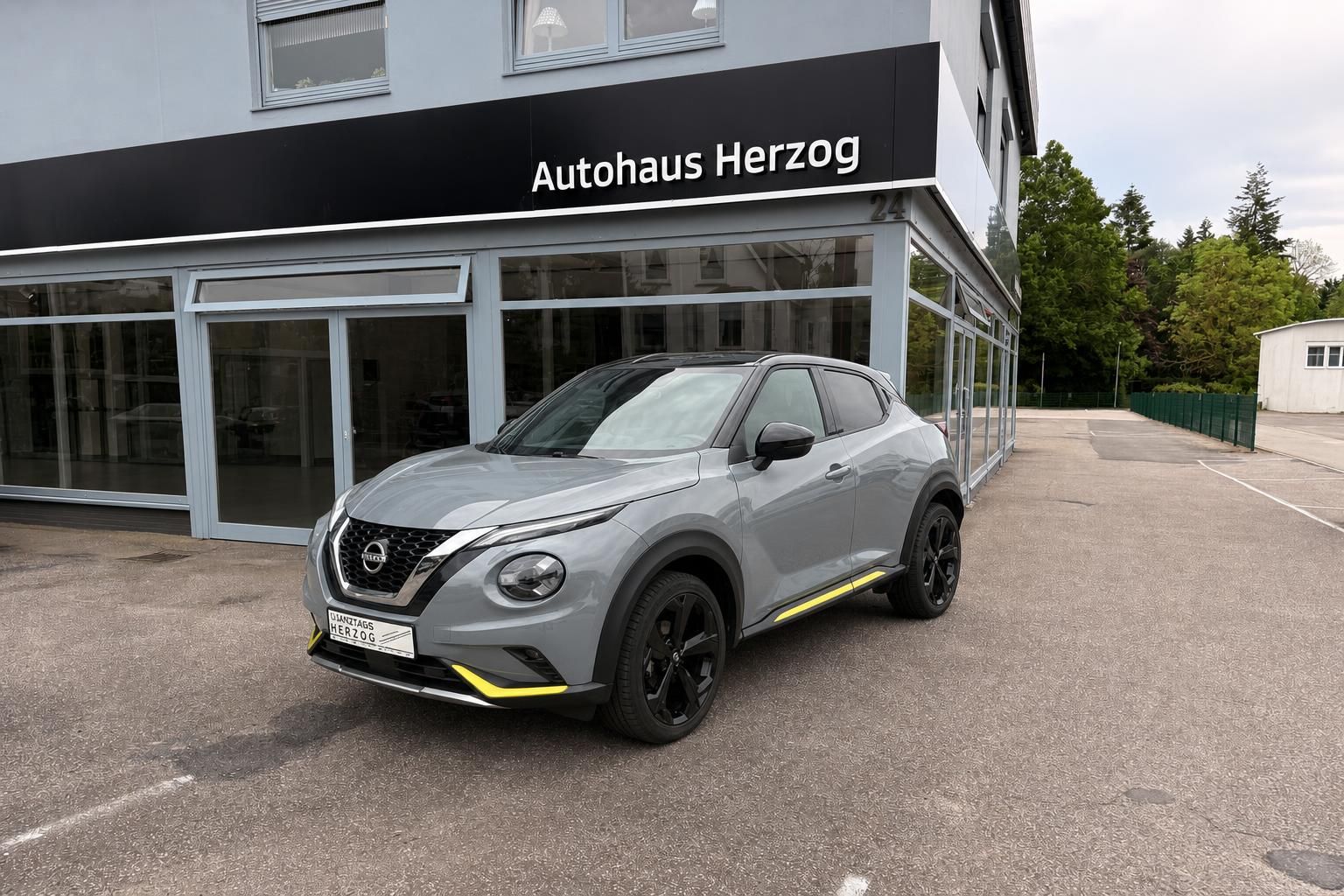 Nissan Juke Frontansicht grau mit schwarzen Felgen vor Autohaus Herzog
