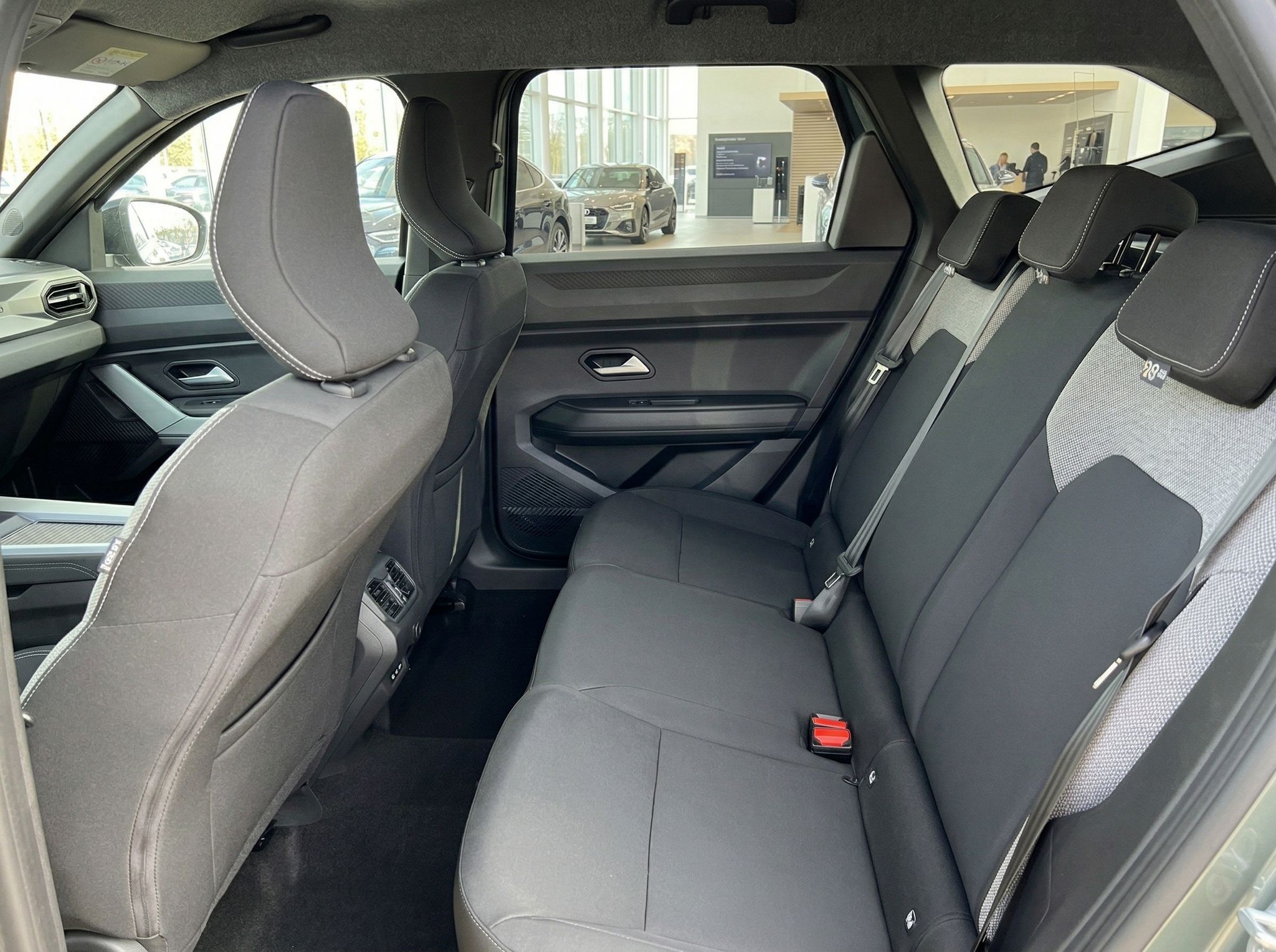 Rücksitzbank eines Fahrzeugs mit grauen Sitzen und Blick nach vorne zum Cockpit