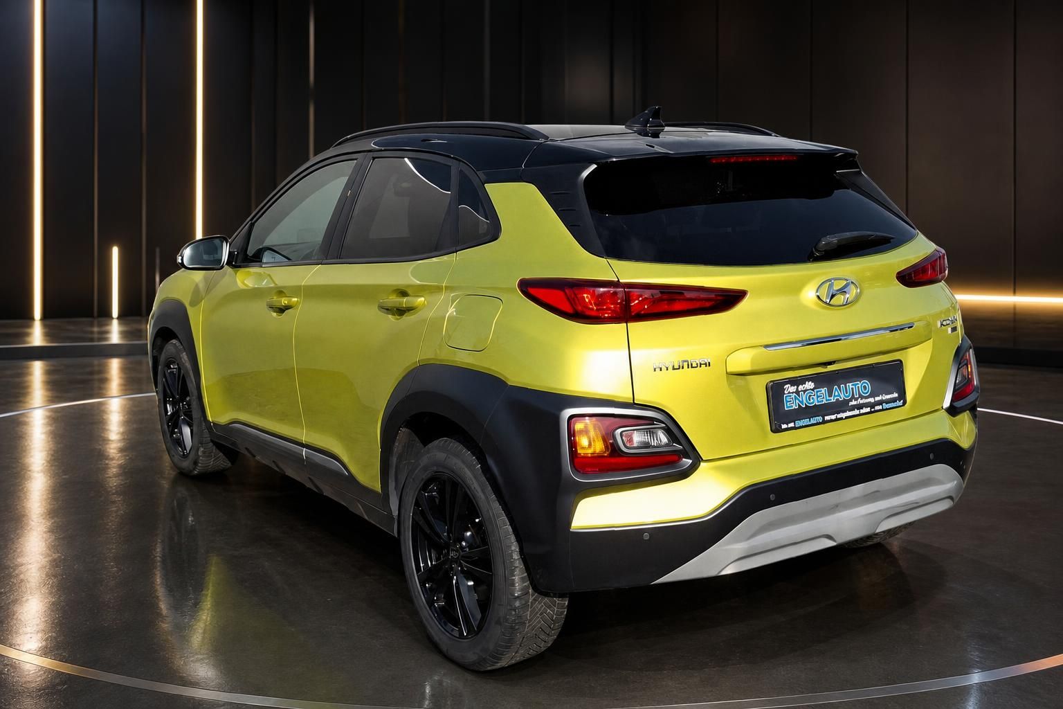 Hyundai Kona SUV in gelb mit schwarzem Dach - Seitenansicht hinten rechts im Showroom