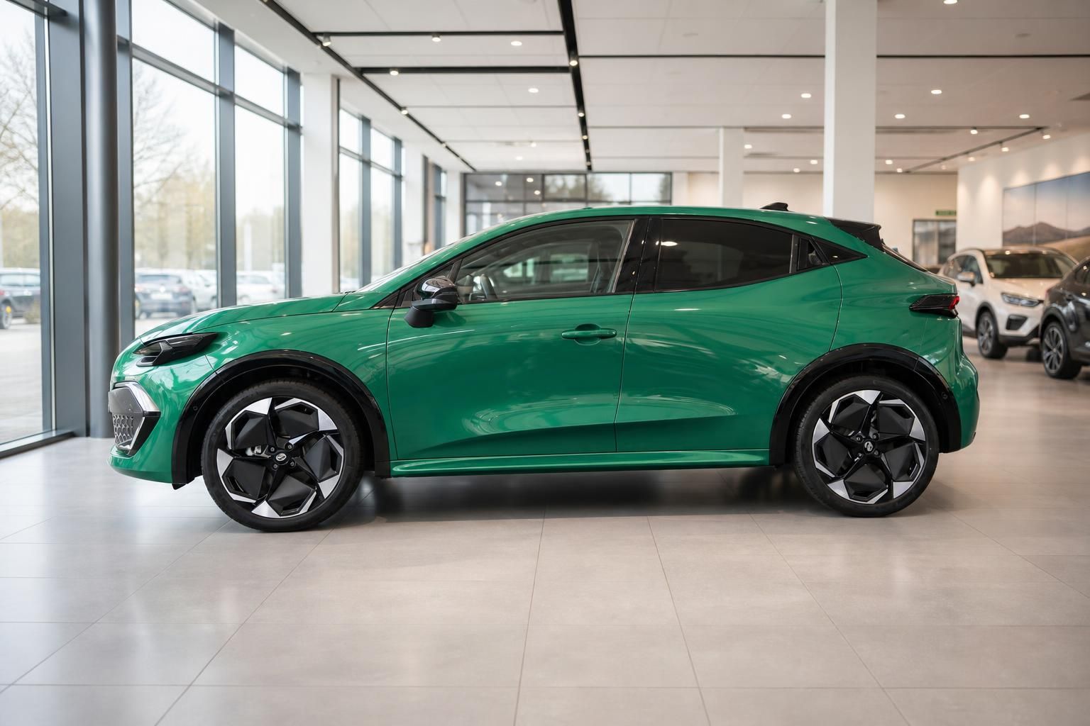 Grüner Renault Clio E-Tech Seitenansicht im Autohaus-Showroom