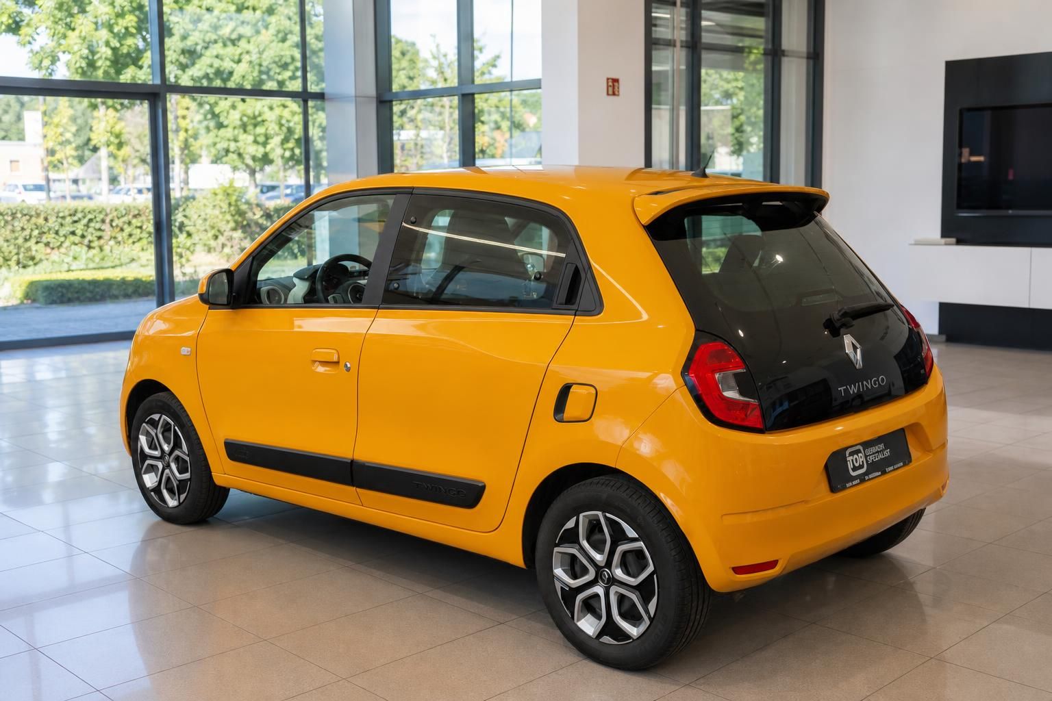 Renault Twingo gelb Seiten-Heckansicht im Showroom – Kleinwagen