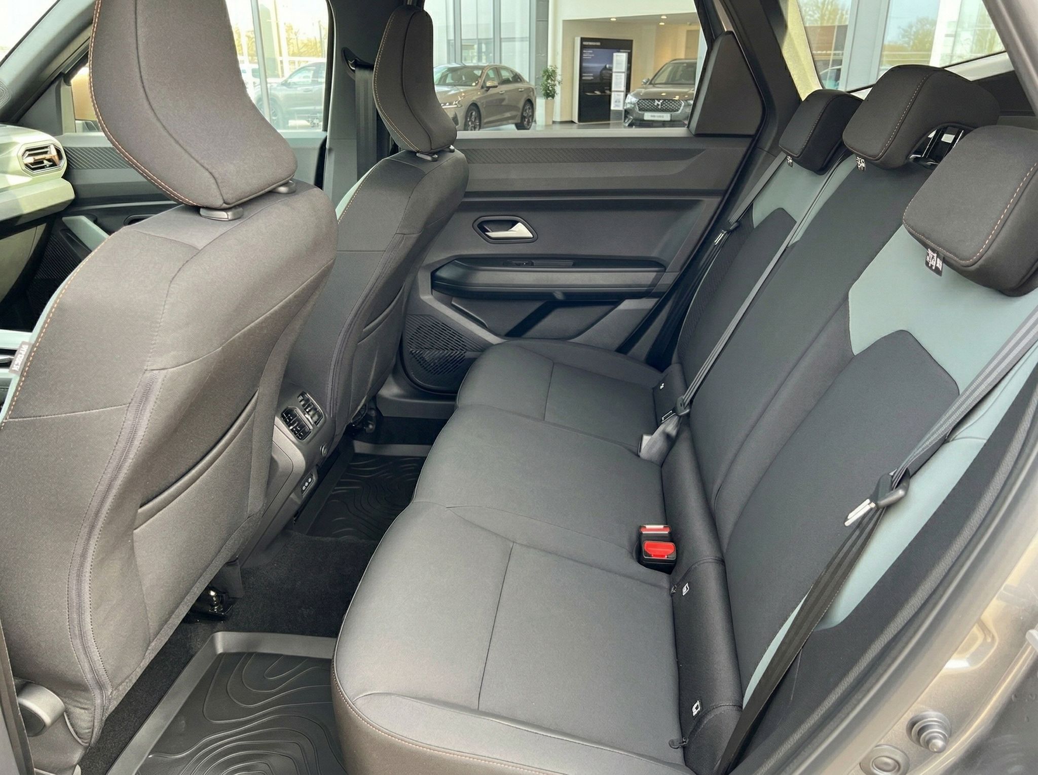 Rücksitzbank mit grauen Polstern und Sicherheitsgurten im Fahrzeuginnenraum