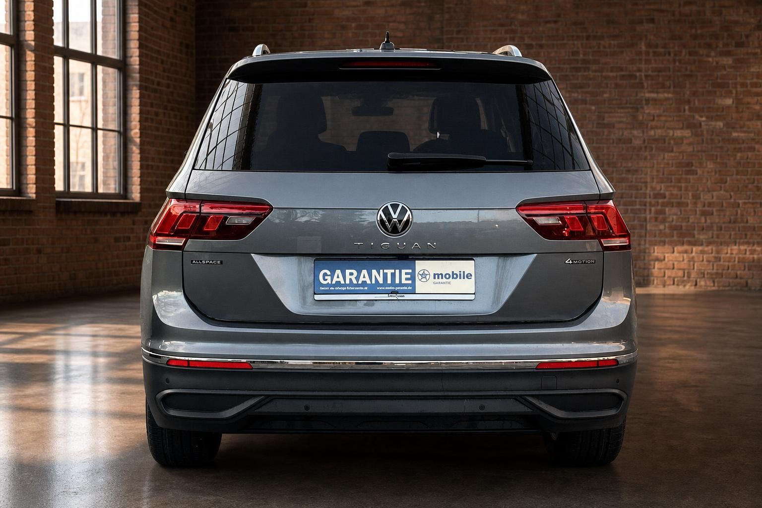 VW Tiguan Allspace 4Motion in Grau, Heckansicht in Loft-Ambiente