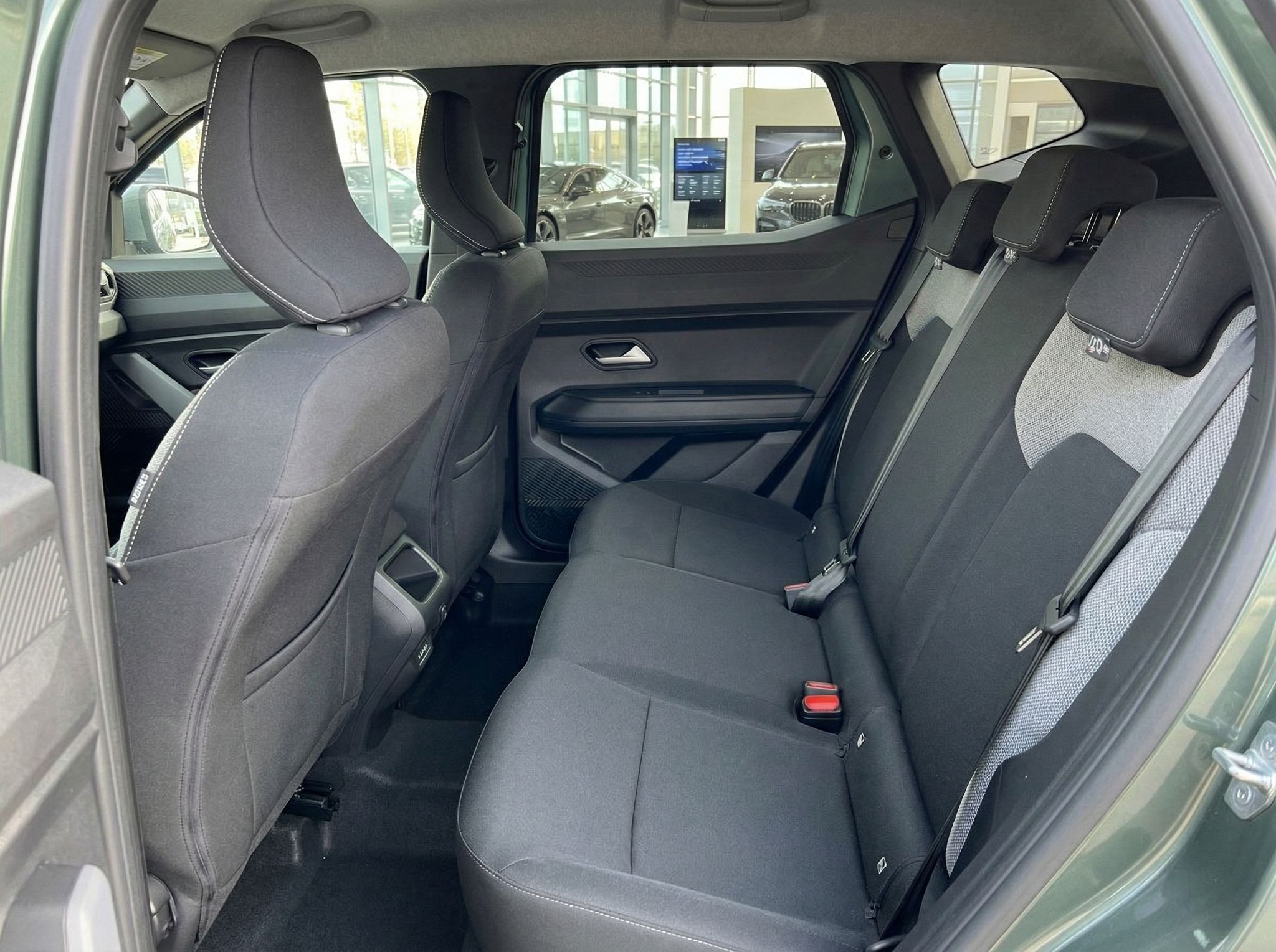 Rückbank eines modernen Fahrzeugs mit grau-weißer Polsterung und Sicherheitsgurten