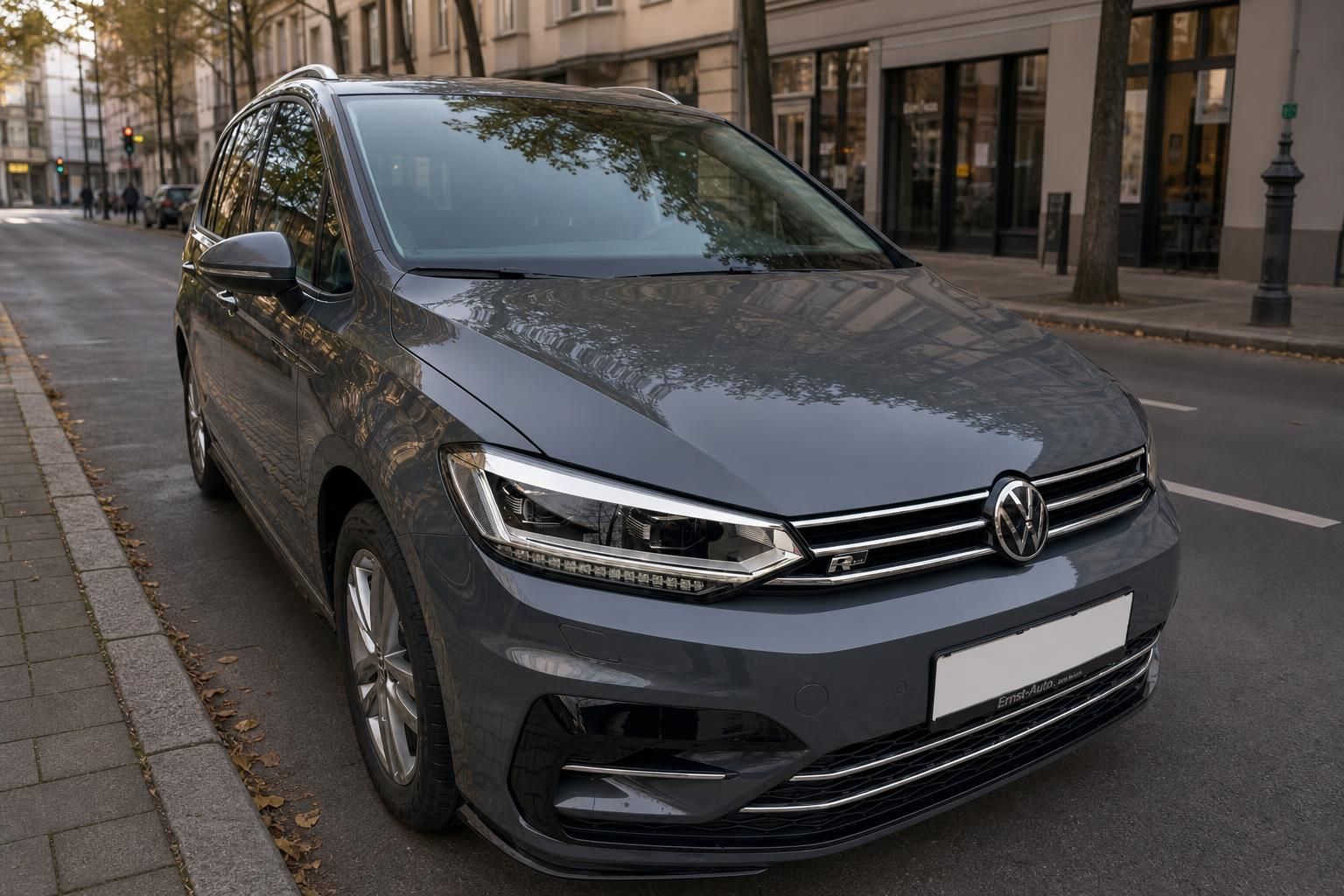 Volkswagen Touran R-Line Frontansicht schräg, grauer Kompaktvan in städtischer Umgebung
