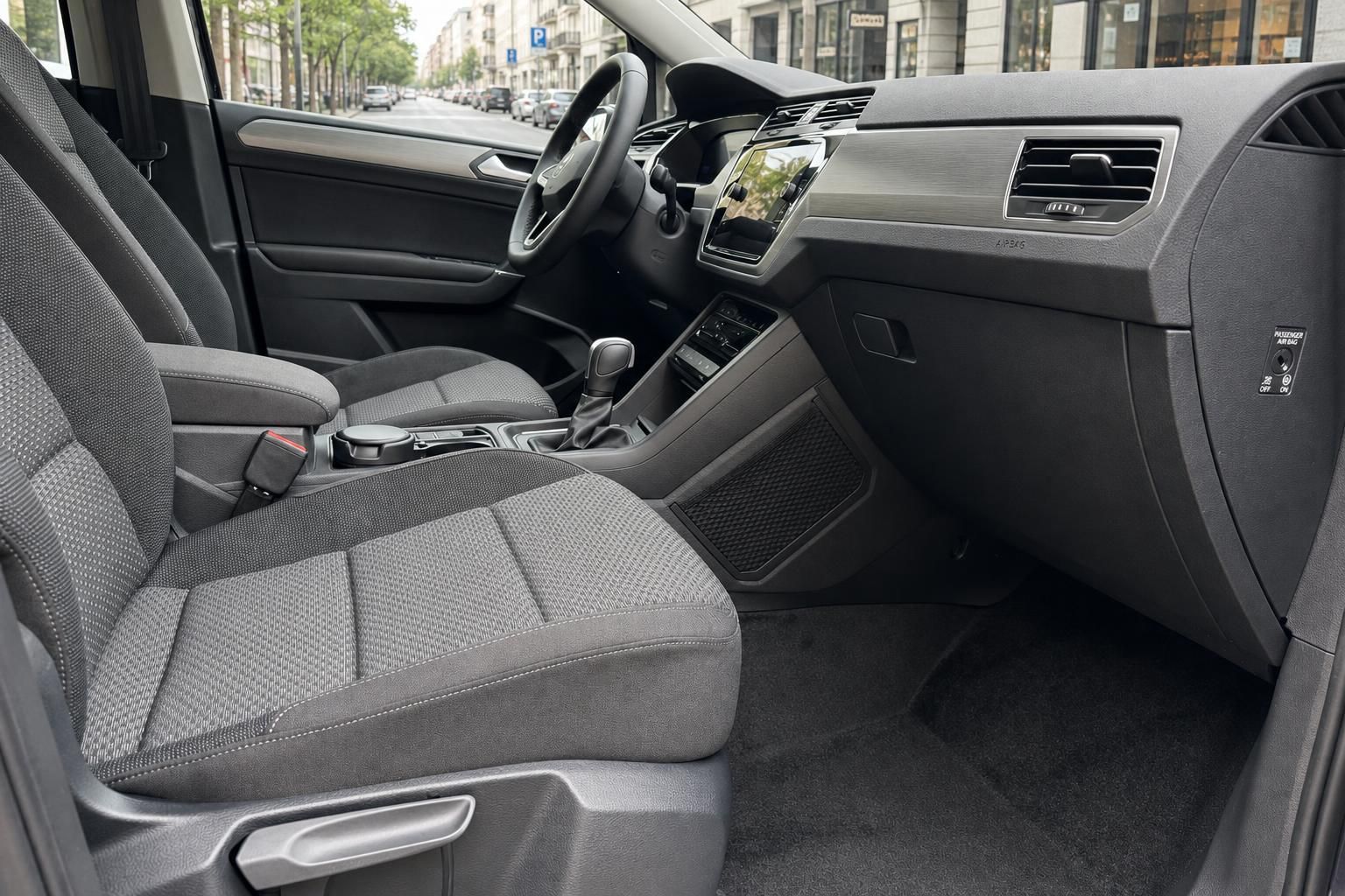 VW Touran Innenraum mit grauen Stoffsitzen, Mittelkonsole und modernem Infotainment-System