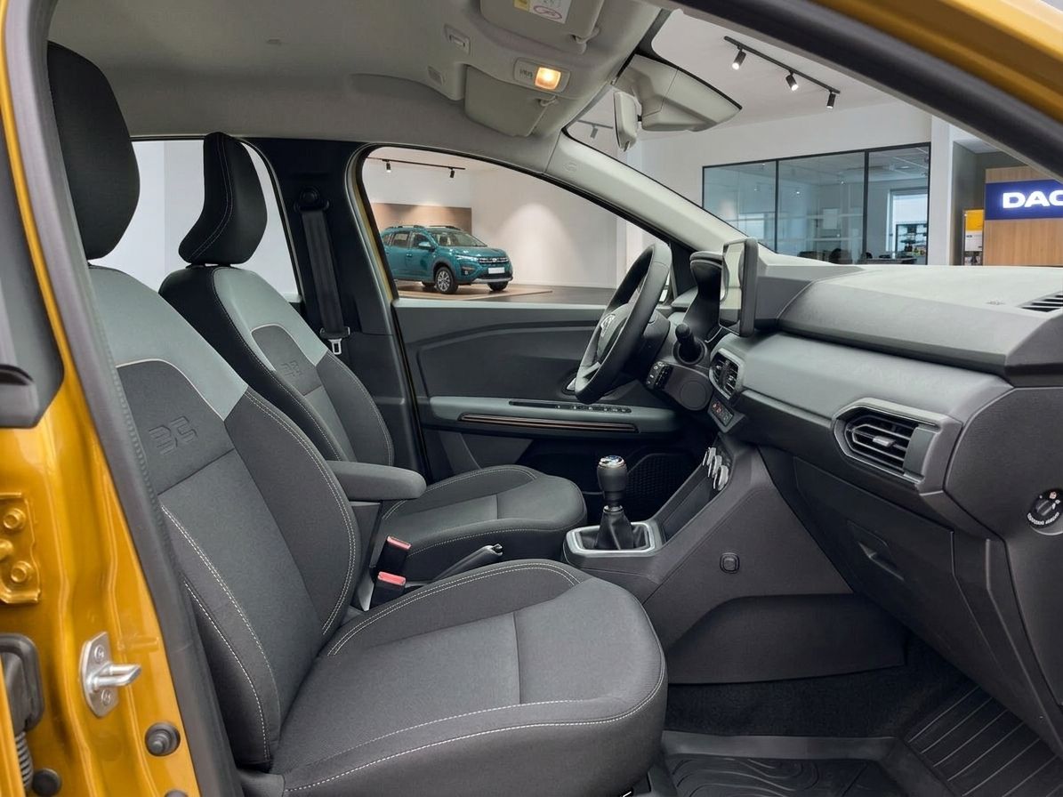 Fahrzeuginnenraum mit Vordersitzen, Armaturenbrett und Blick auf Autohaus durch Fenster