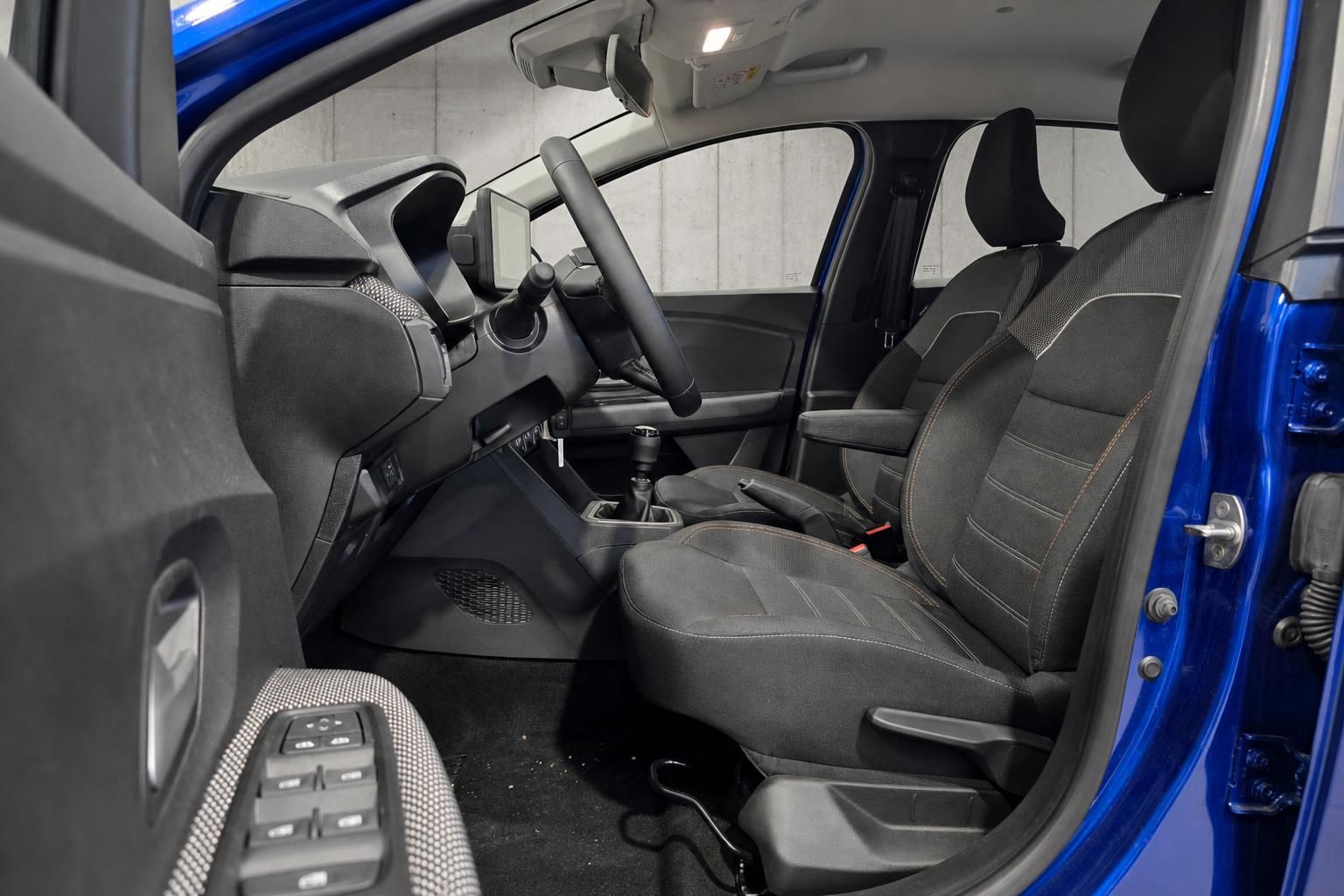 Blick auf Vordersitze und Cockpit eines blauen Dacia mit offener Tür