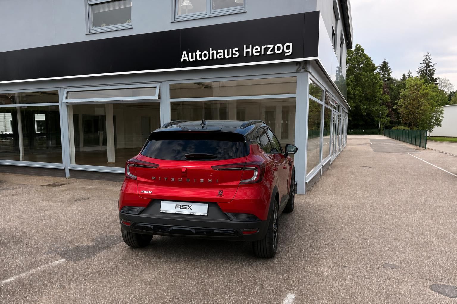 Roter Mitsubishi ASX von hinten geparkt beim Autohaus Herzog