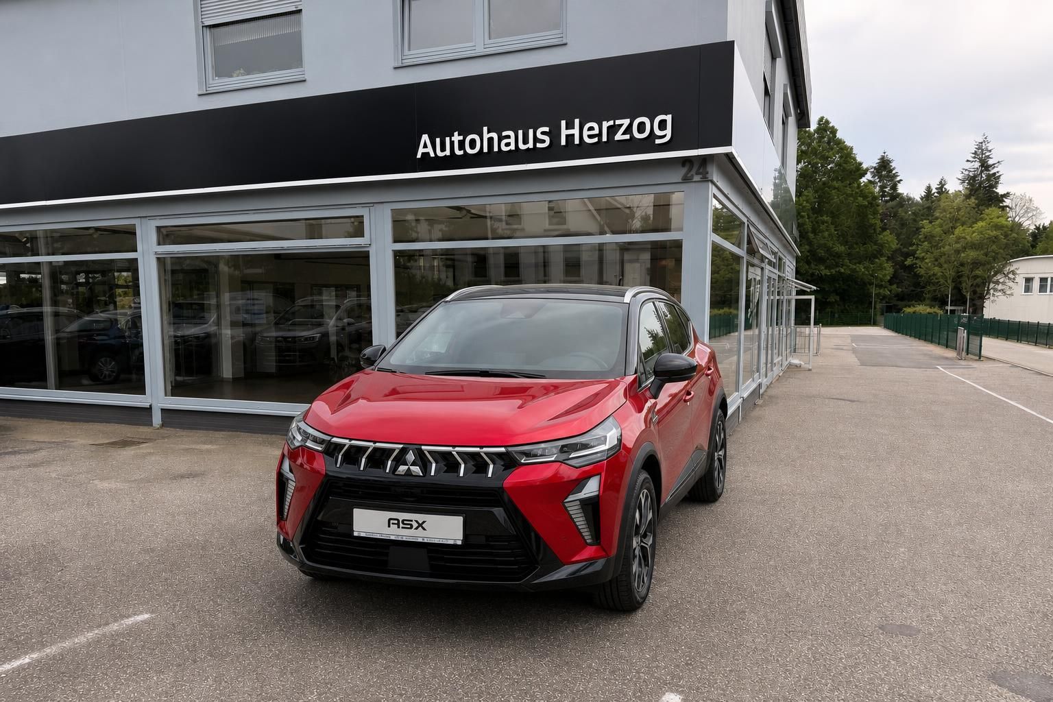 Roter Mitsubishi ASX von vorn geparkt beim Autohaus Herzog