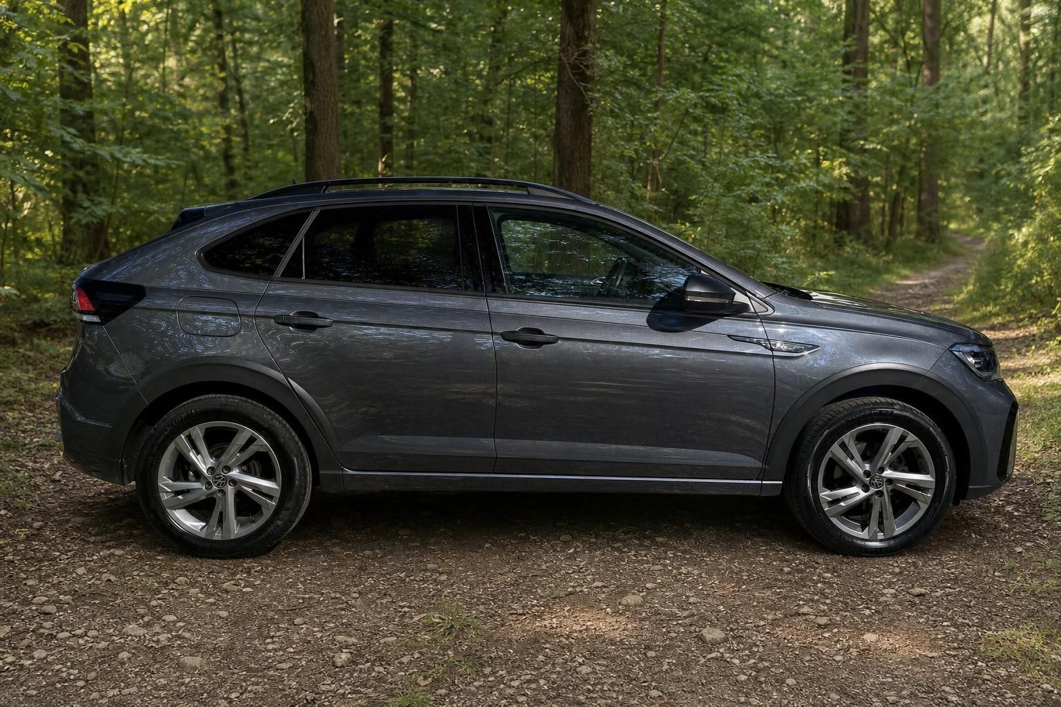 Volkswagen Taigo graue Seitenansicht Fahrerseite zwischen Bäumen