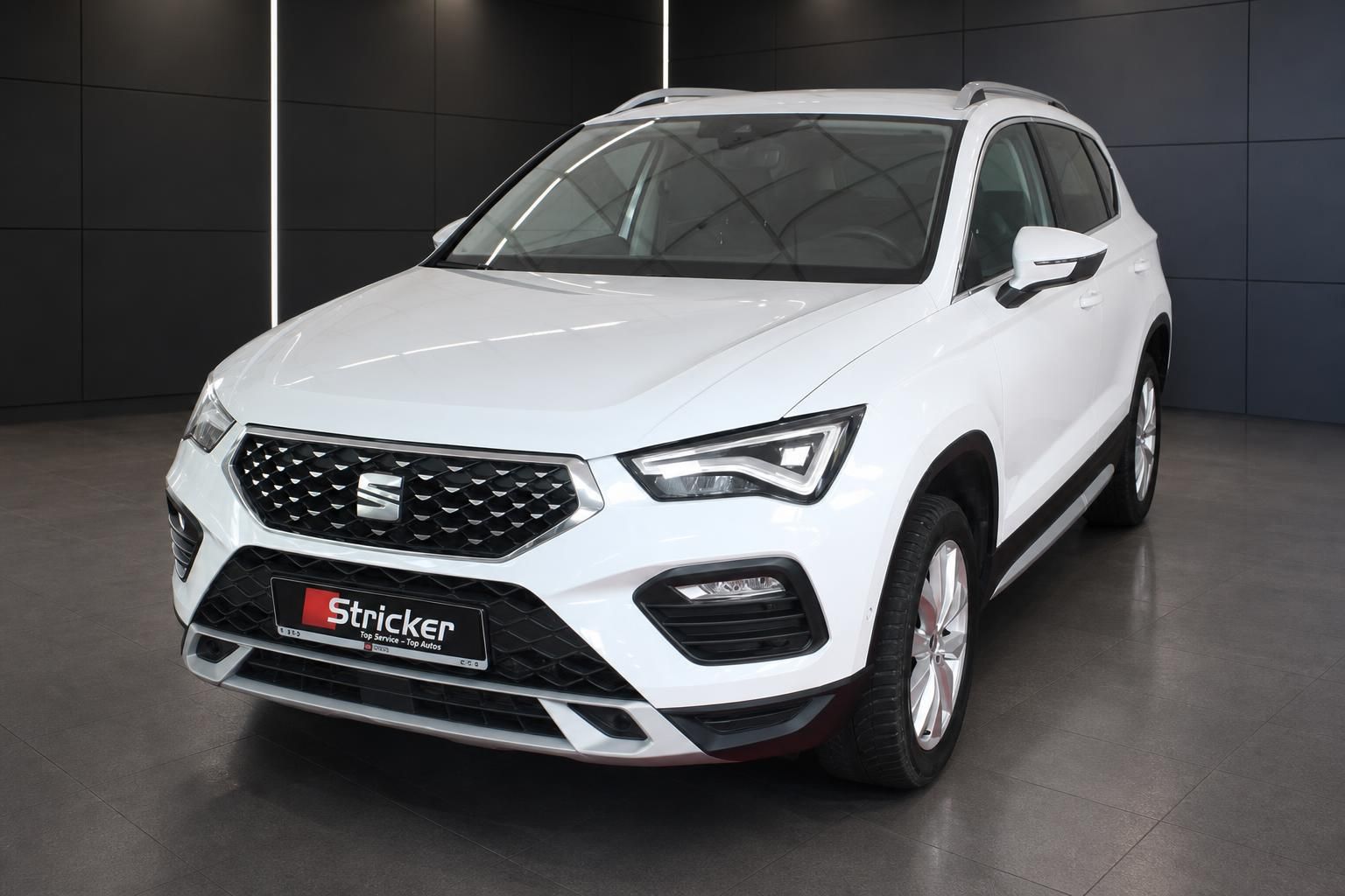 SEAT Ateca weiss Frontansicht schräg links im dunklen Showroom – SUV Gebrauchtwagen Stricker