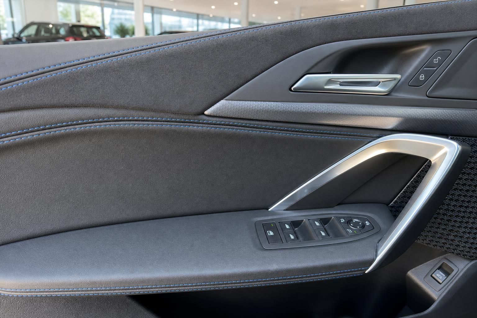 Türverkleidung BMW mit Bedienelementen und blauer Ziernaht im Detail