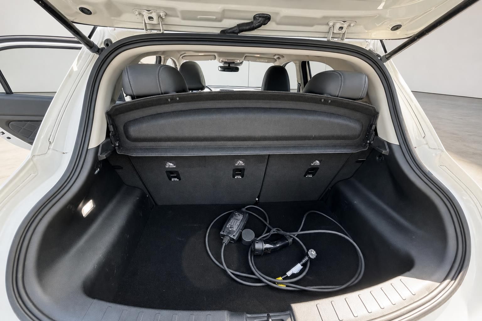 Kofferraum eines Fahrzeugs mit schwarzer Ausstattung und Ladekabel für Elektroauto