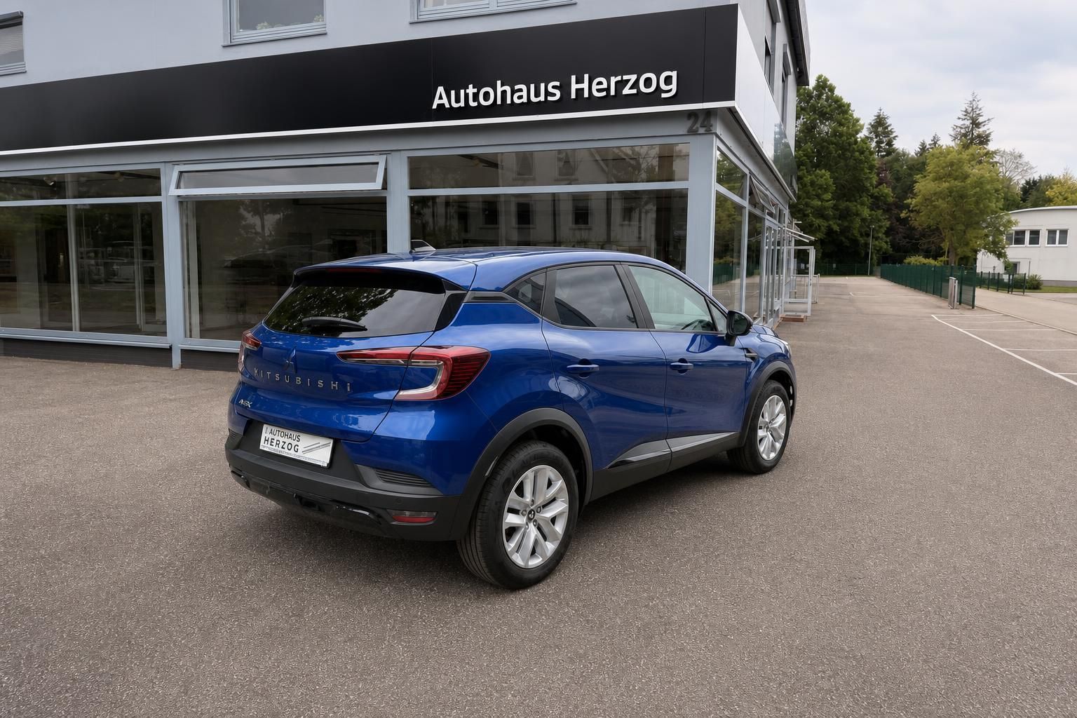 Mitsubishi ASX blau Seiten-Heckansicht vor Autohaus Herzog Fassade