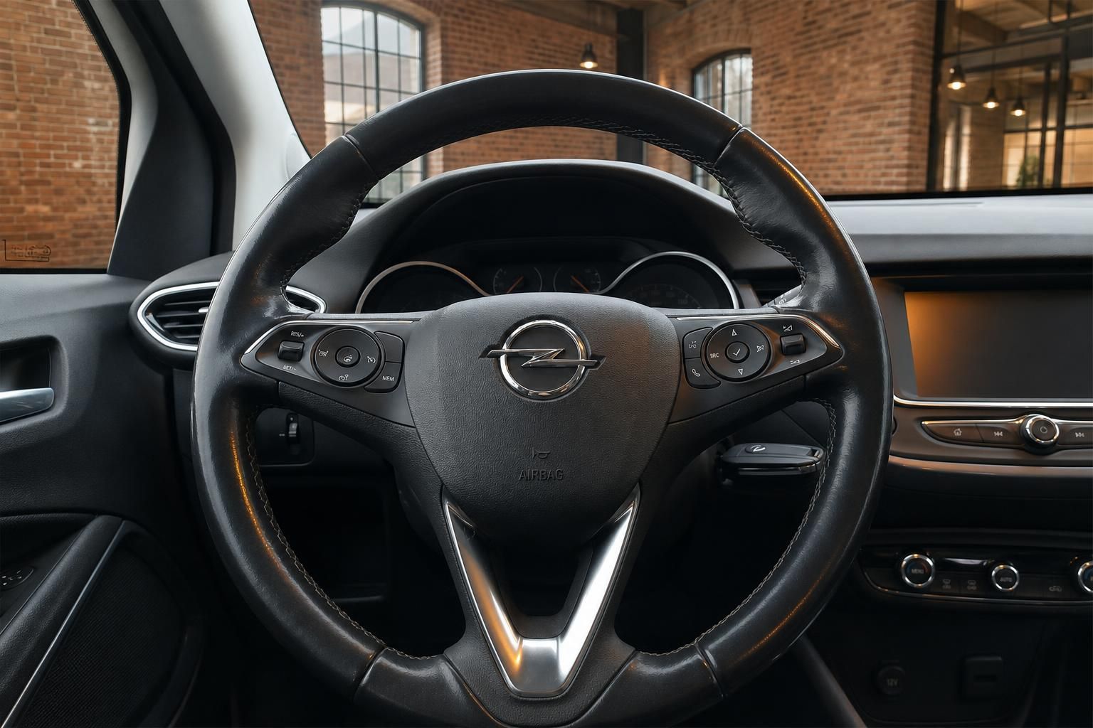 Opel Lederlenkrad mit Multifunktionstasten und Opel-Logo im Fahrzeuginnenraum