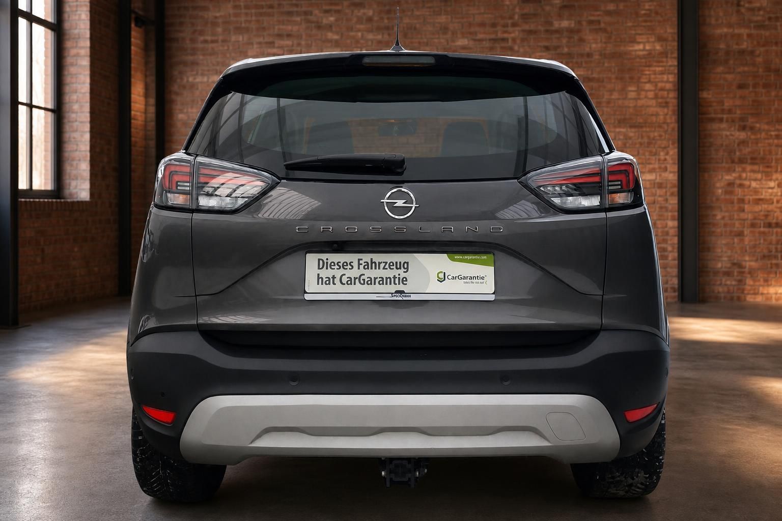 Opel Crossland grau Heckansicht gerade mit Opel-Logo, Modellschriftzug und Anhängerkupplung