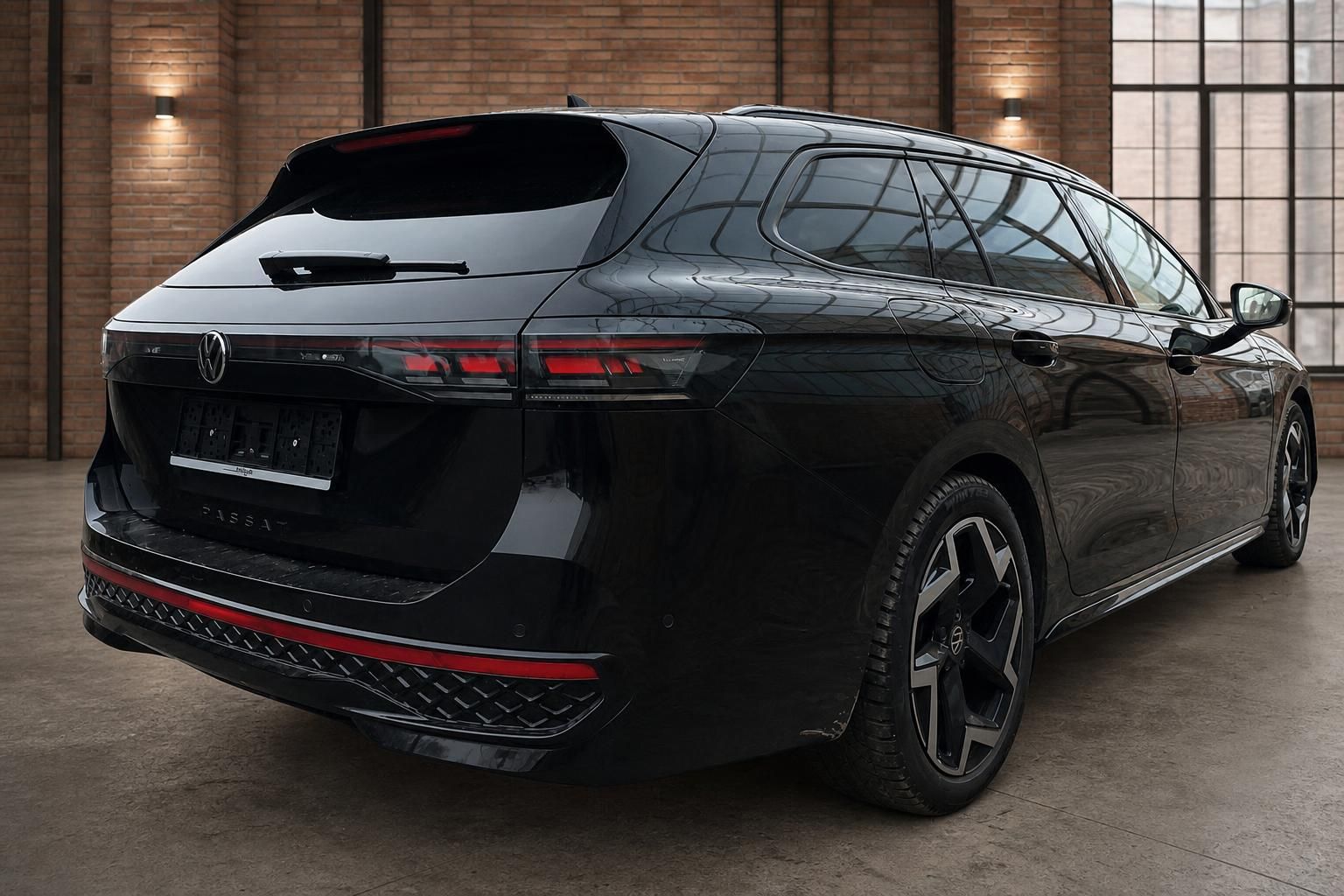 VW Passat Variant schwarz schräge Heckansicht mit Sportfelgen in moderner Industriehalle