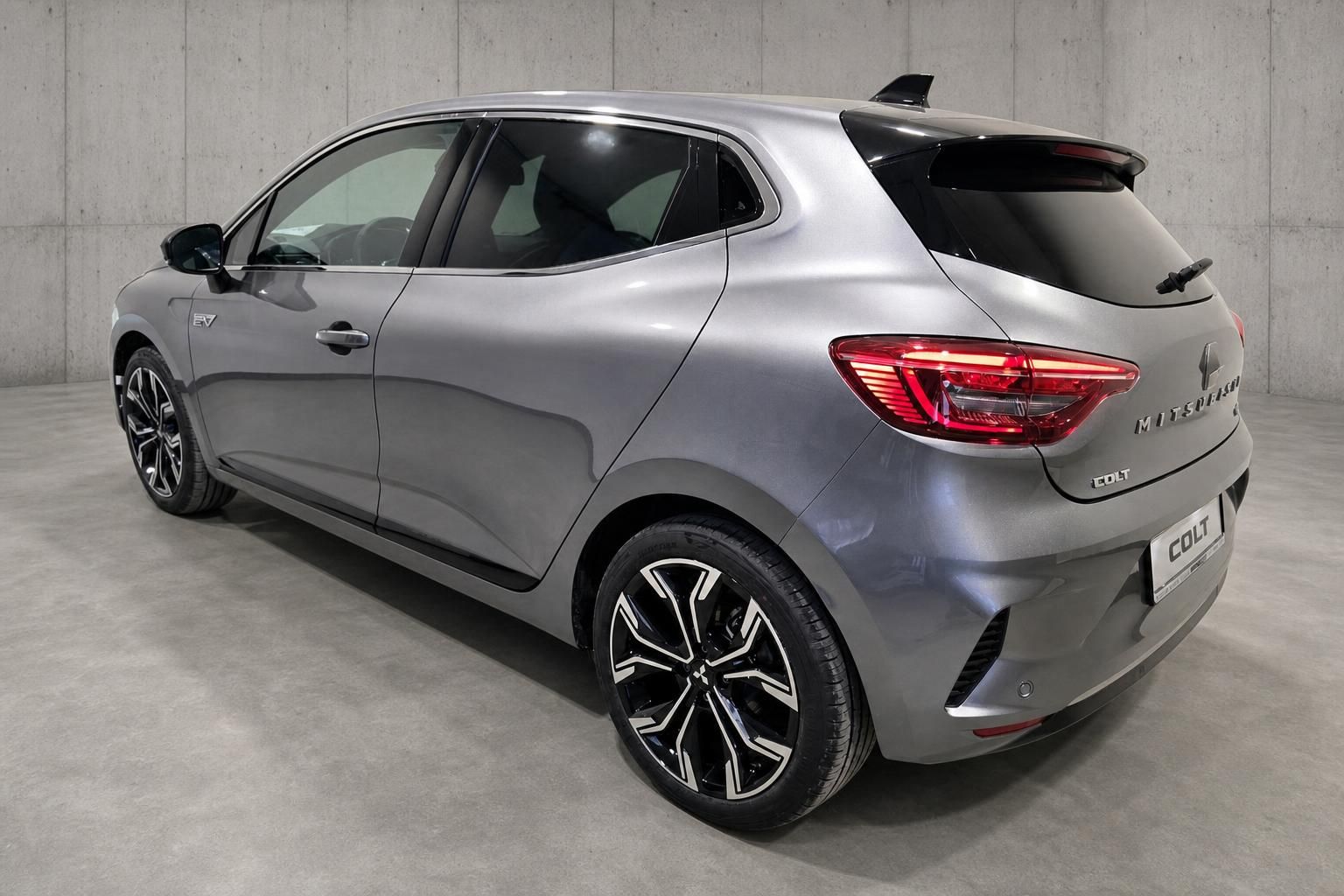 Grauer Mitsubishi Colt Elektro EV Heckansicht mit Alufelgen in Studioumgebung
