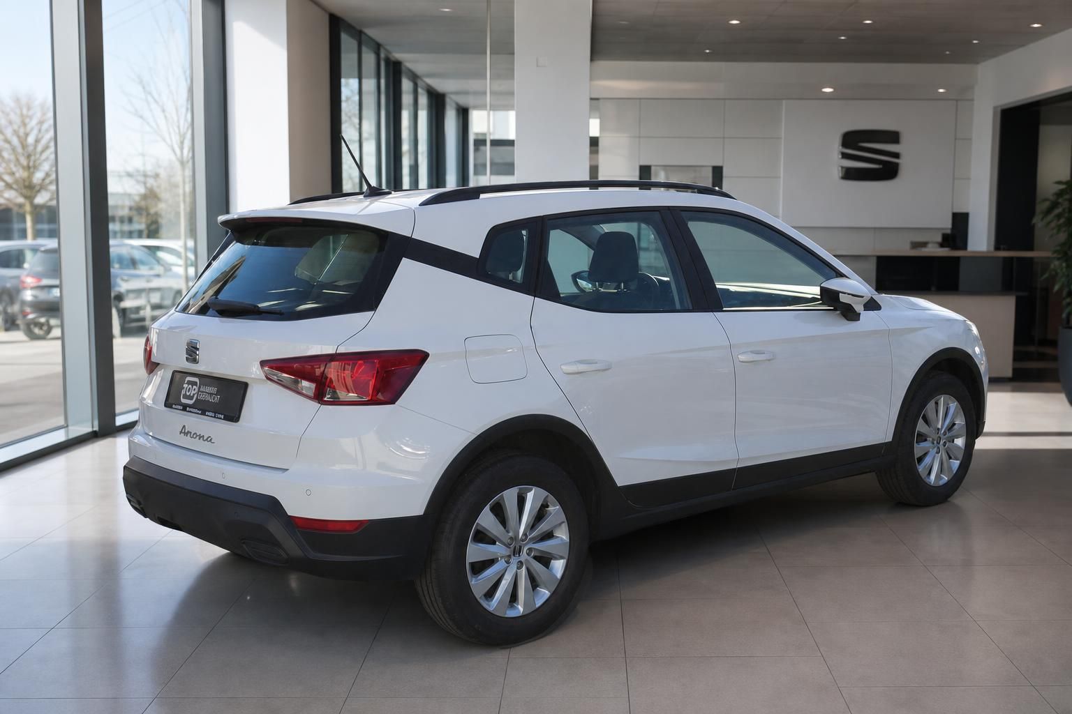 Weißer SEAT Arona SUV von hinten im modernen Autohaus-Showroom mit großen Fenstern