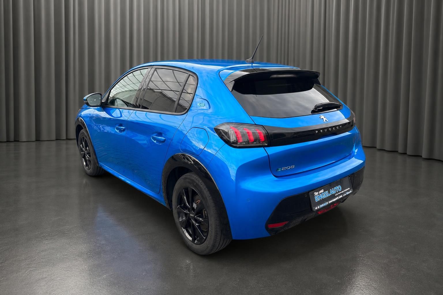 Peugeot e-208 blau Heckansicht schräg im Showroom