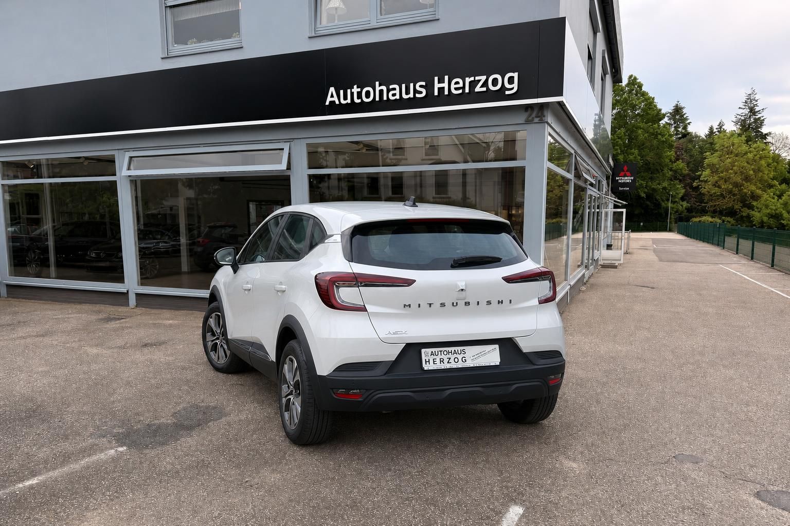 Mitsubishi SUV weiß Heckansicht vor Autohaus Herzog Gebäude mit Händlerkennzeichen
