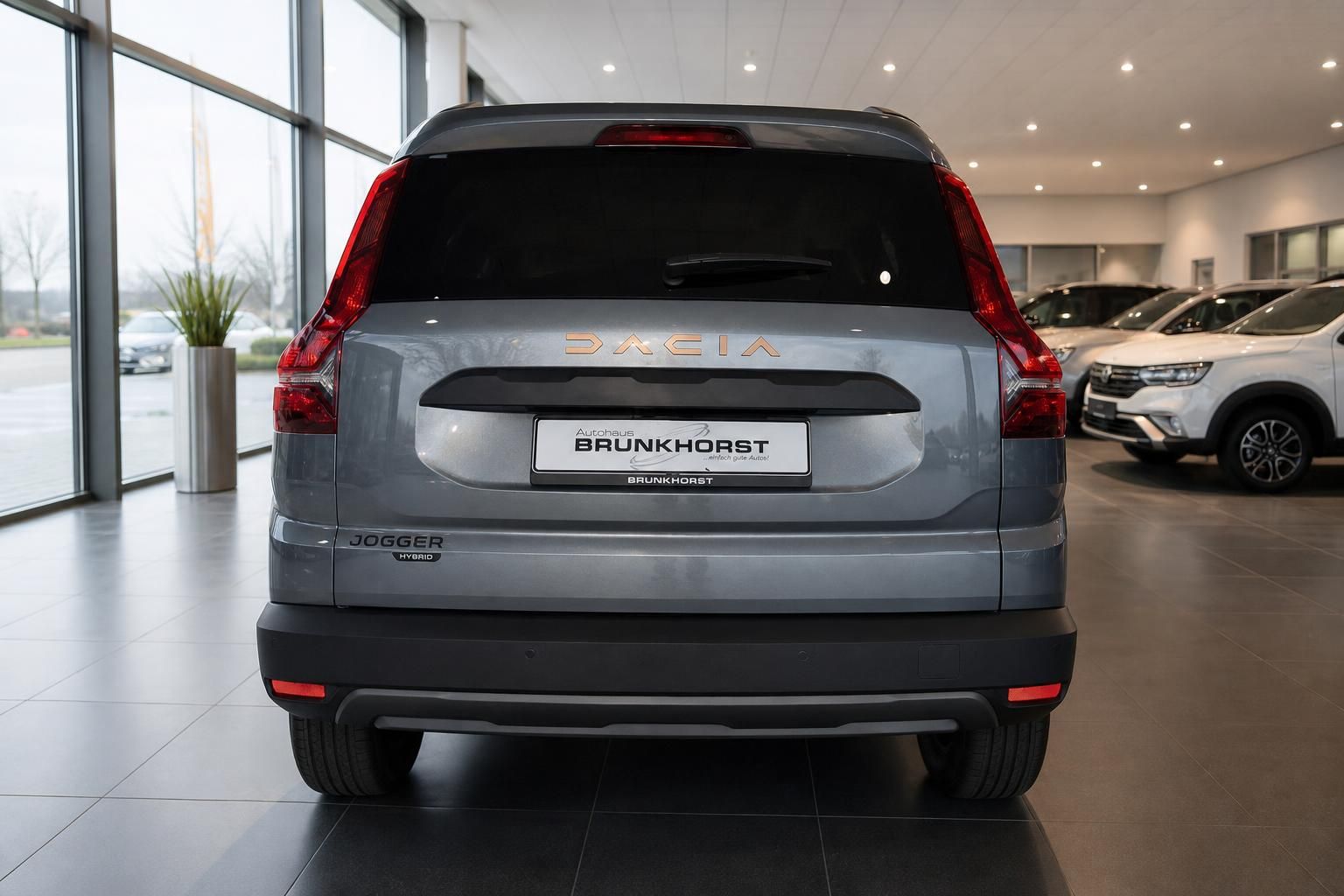 Dacia Jogger grau metallic Heckansicht SUV im Autohaus mit Hybrid Kennzeichnung