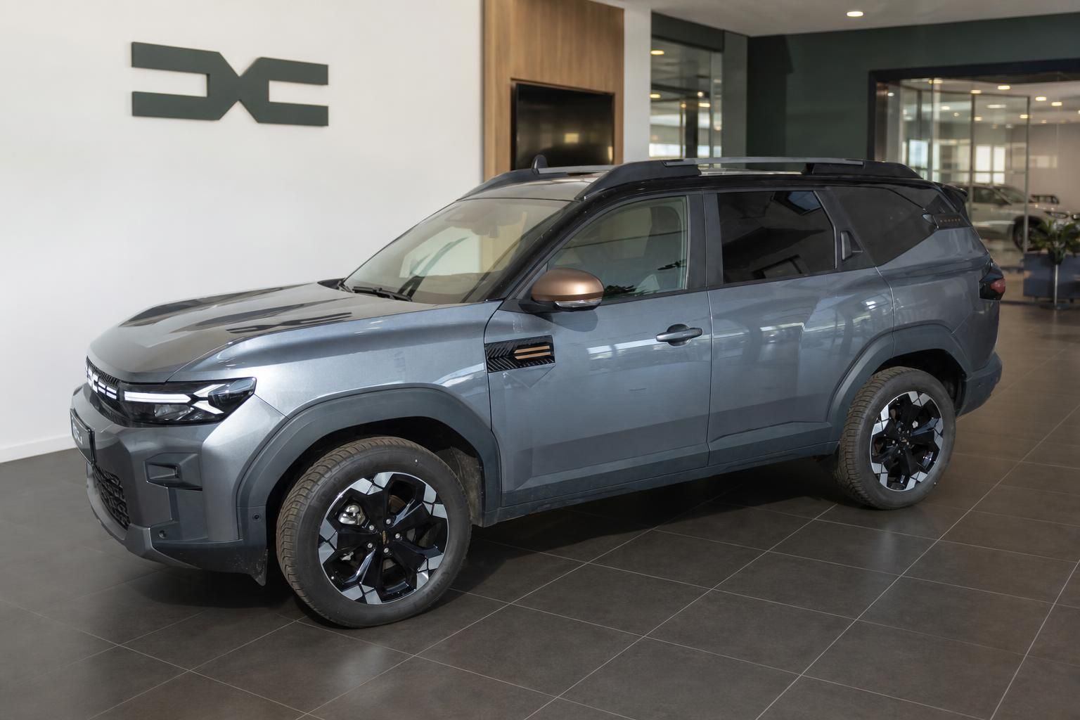 Dacia Bigster SUV in Grau, Seitenansicht im Autohaus-Showroom