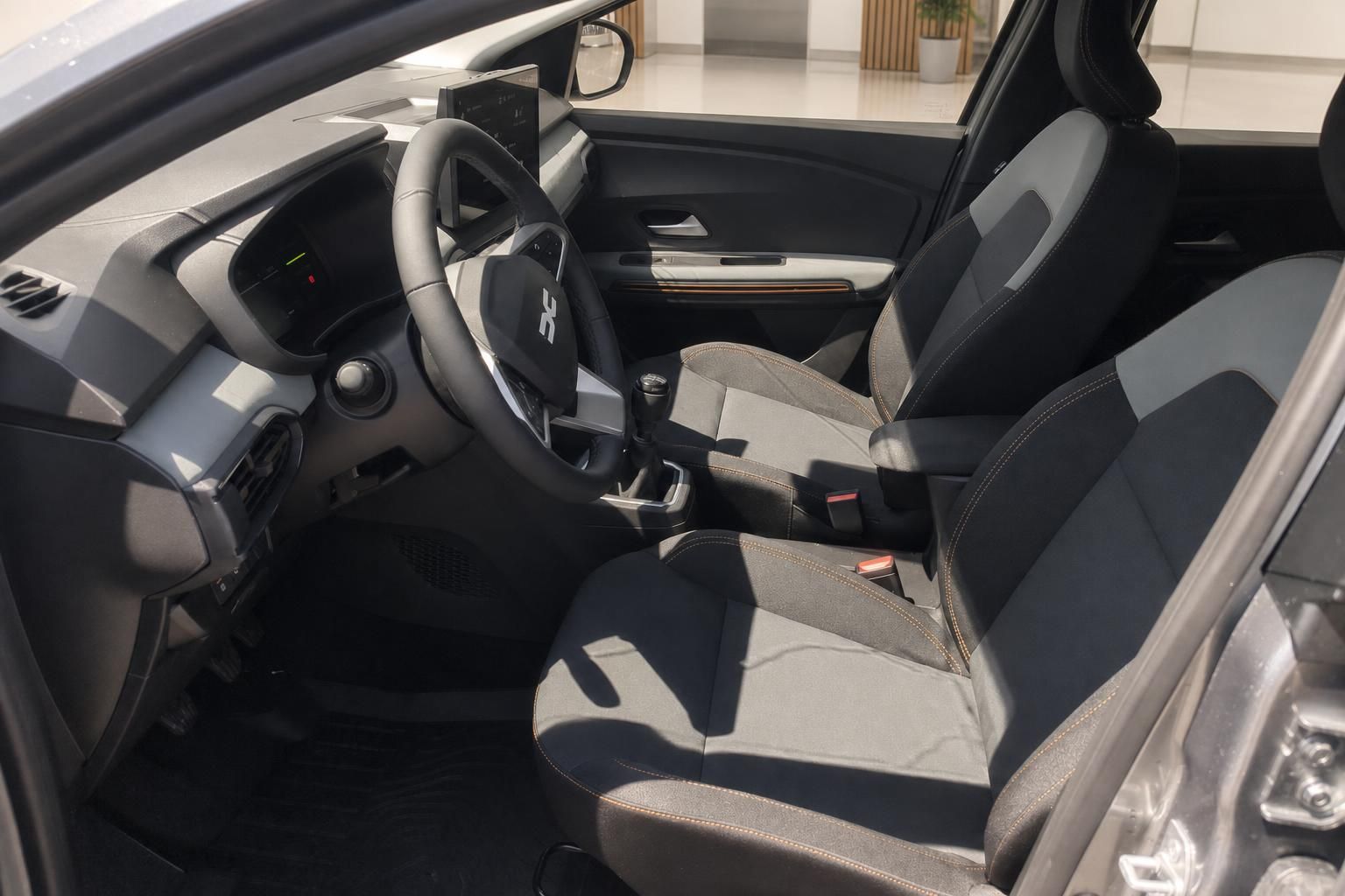 Dacia Sandero Stepway Innenraum – Vordersitze mit grau-schwarzem Stoff und oranger Ziernaht