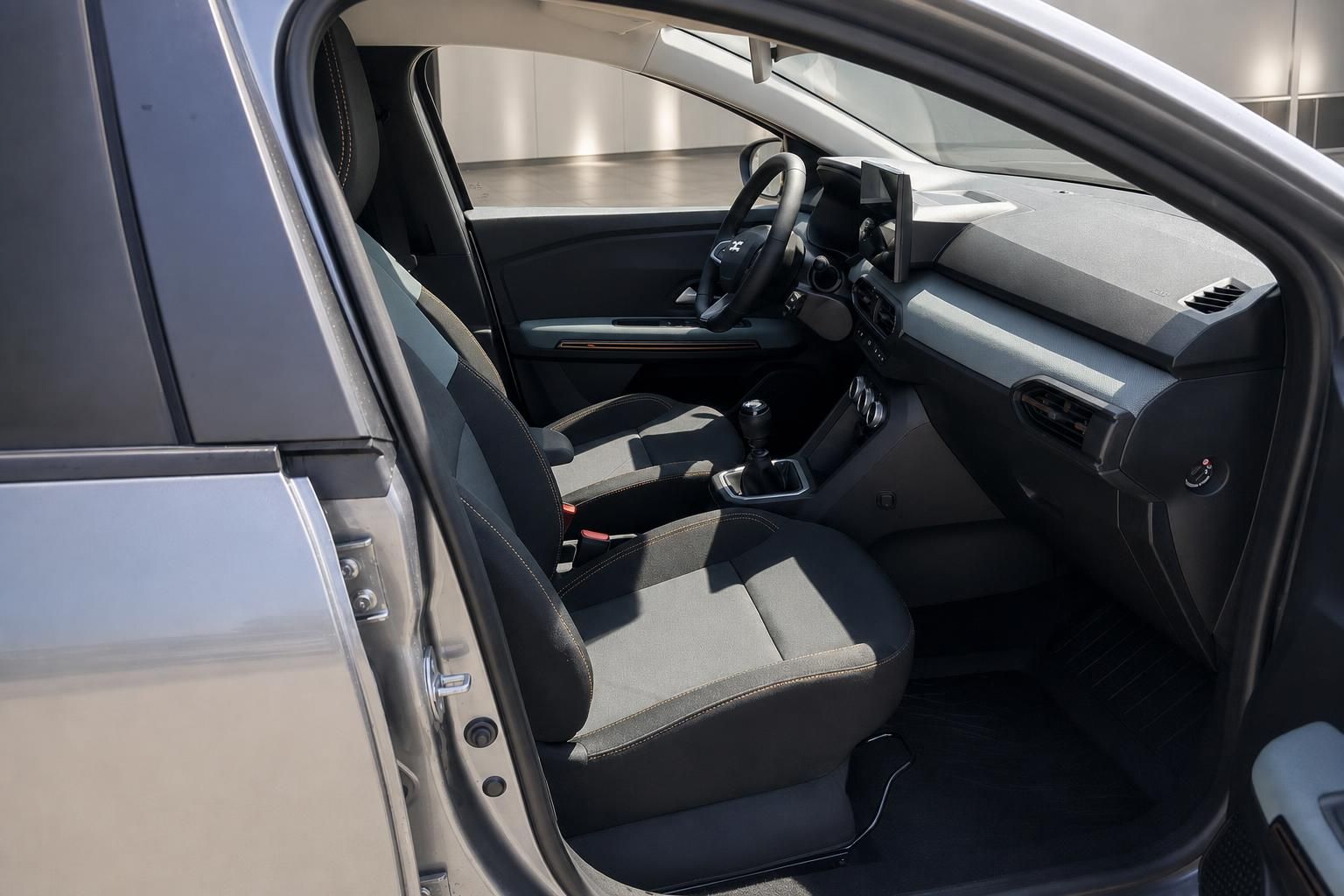 Dacia Fahrzeuginnenraum Vordersitze grau mit Schaltgetriebe, geöffnete Fahrertür