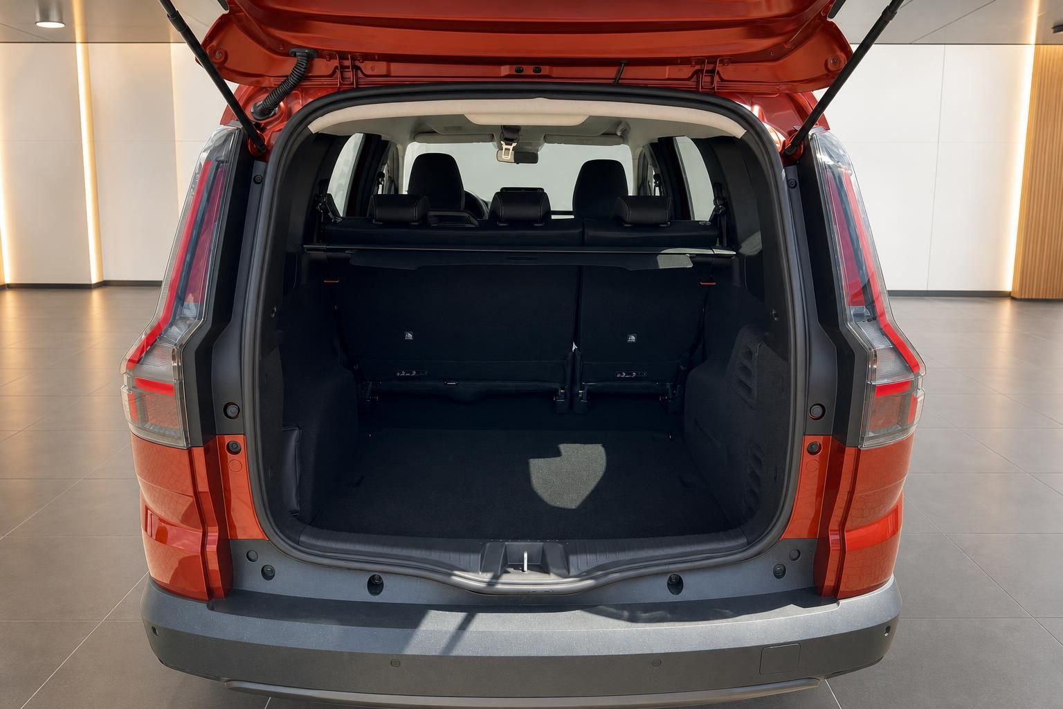 Kofferraum eines orangenen SUV mit geöffneter Heckklappe und schwarzer Innenausstattung