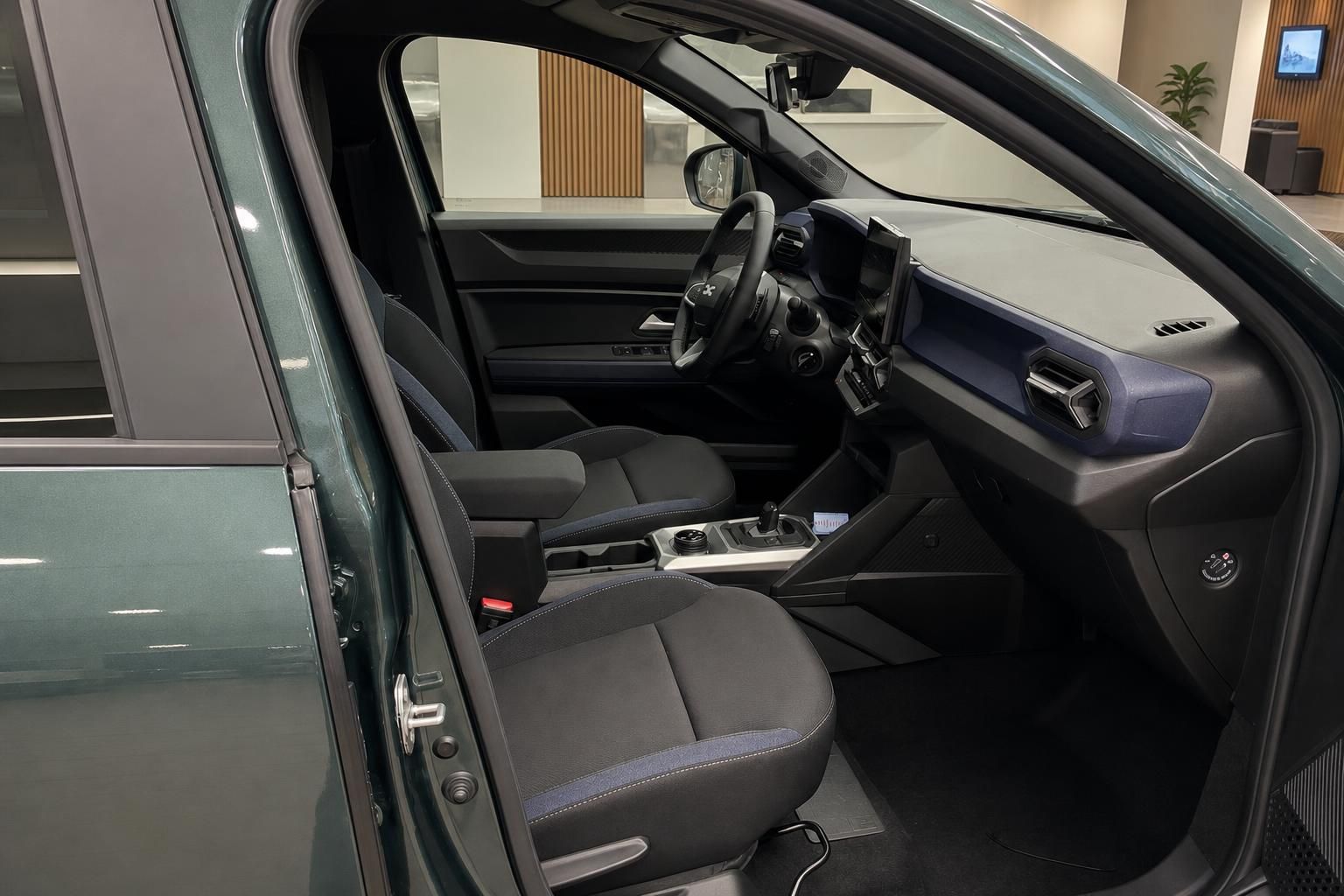 Dacia SUV Innenraum Fahrerseite mit schwarzen Stoffsitzen und blauer Armaturenbrett-Akzentfarbe