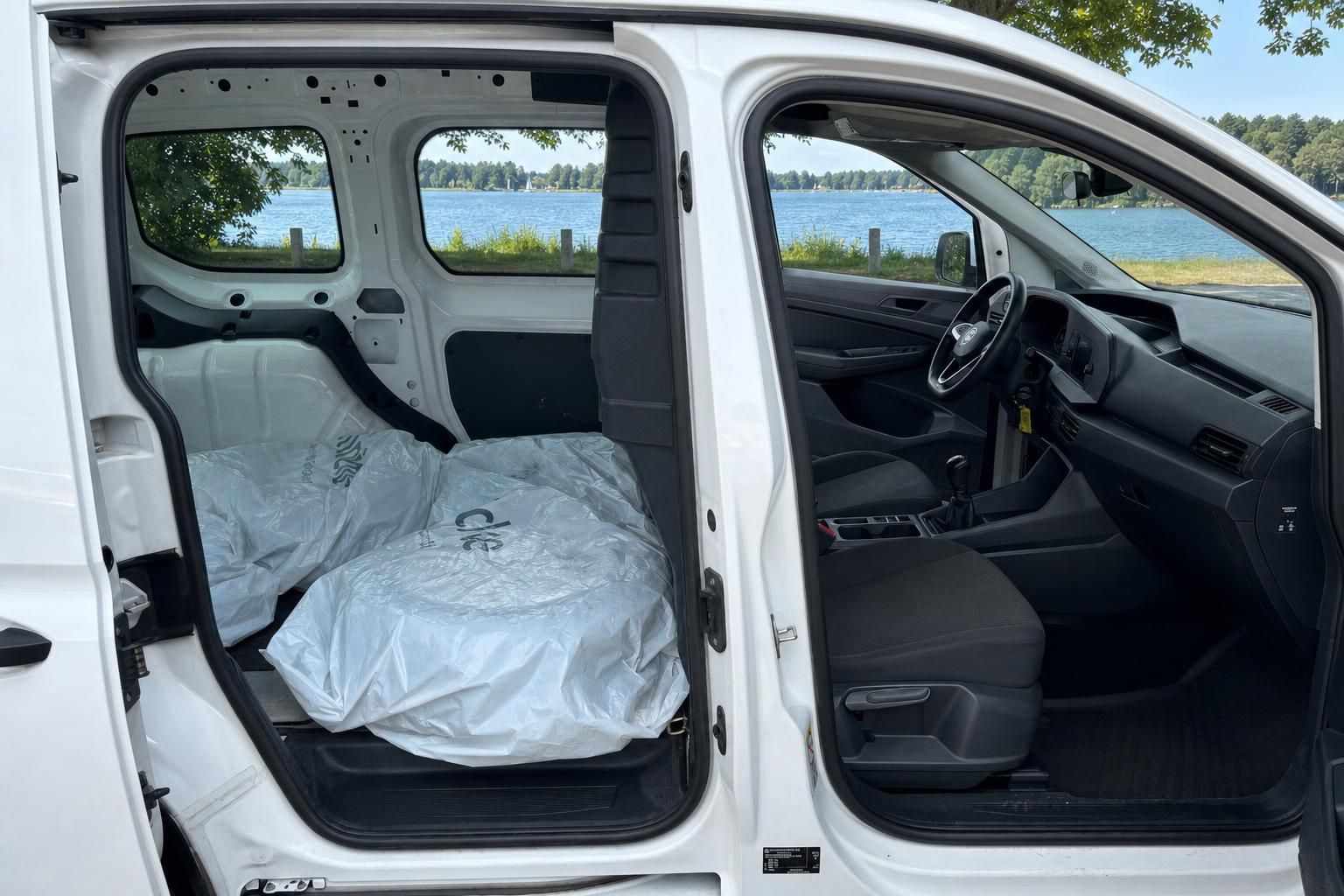 Fahrzeug mit geöffneten Türen zeigt Innenraum und Ladebereich mit verpackten Sitzen