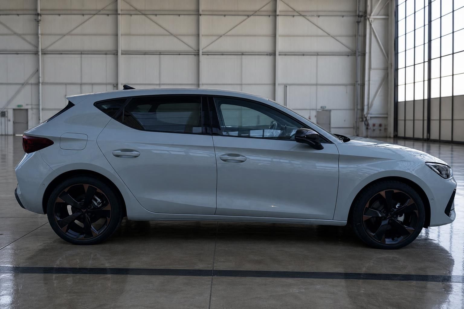 SEAT Cupra Leon in weiß - Seitenansicht mit schwarzen Felgen in moderner Fahrzeughalle