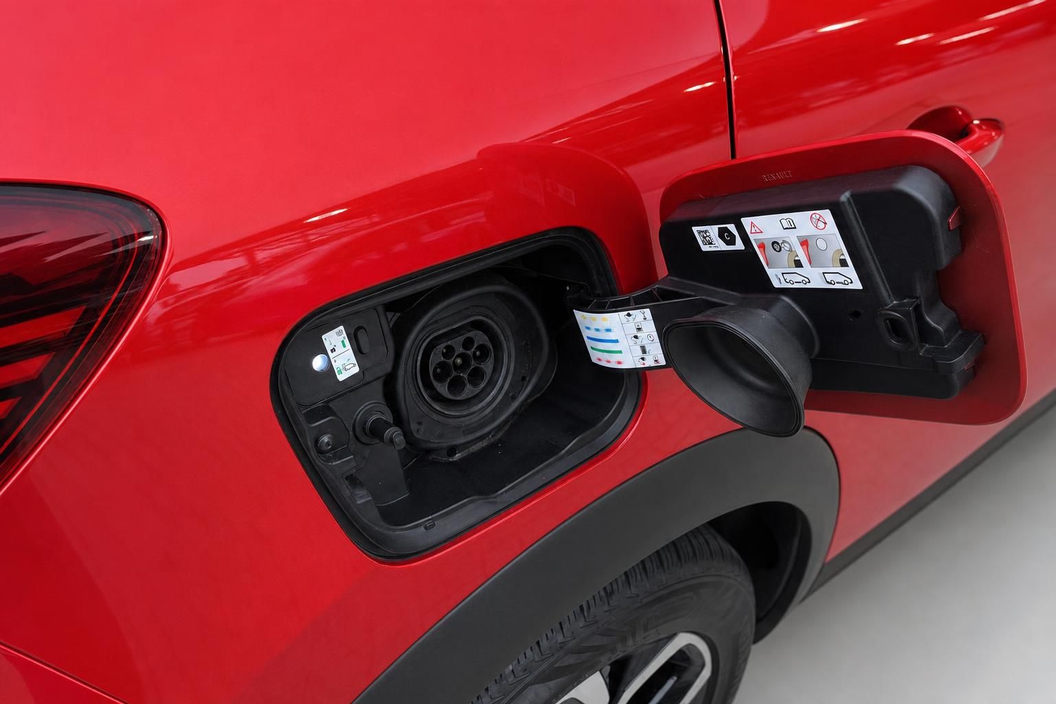 Ladeanschluss und Tankdeckel eines roten Plug-in-Hybrid Fahrzeugs