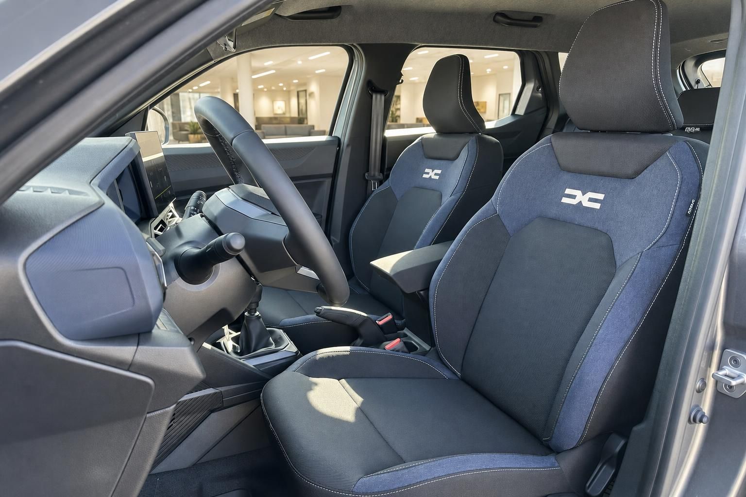 Dacia Duster Innenraum – Vordersitze mit blau-schwarzem Stoffbezug und Dacia-Logo