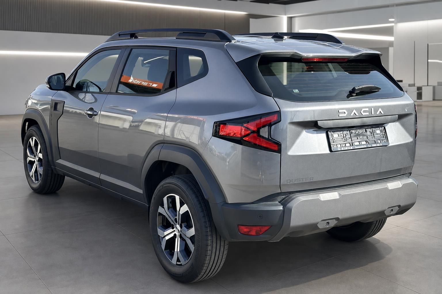 Dacia Duster SUV grau Heckansicht schräg im Showroom mit Dachreling und LED-Rückleuchten